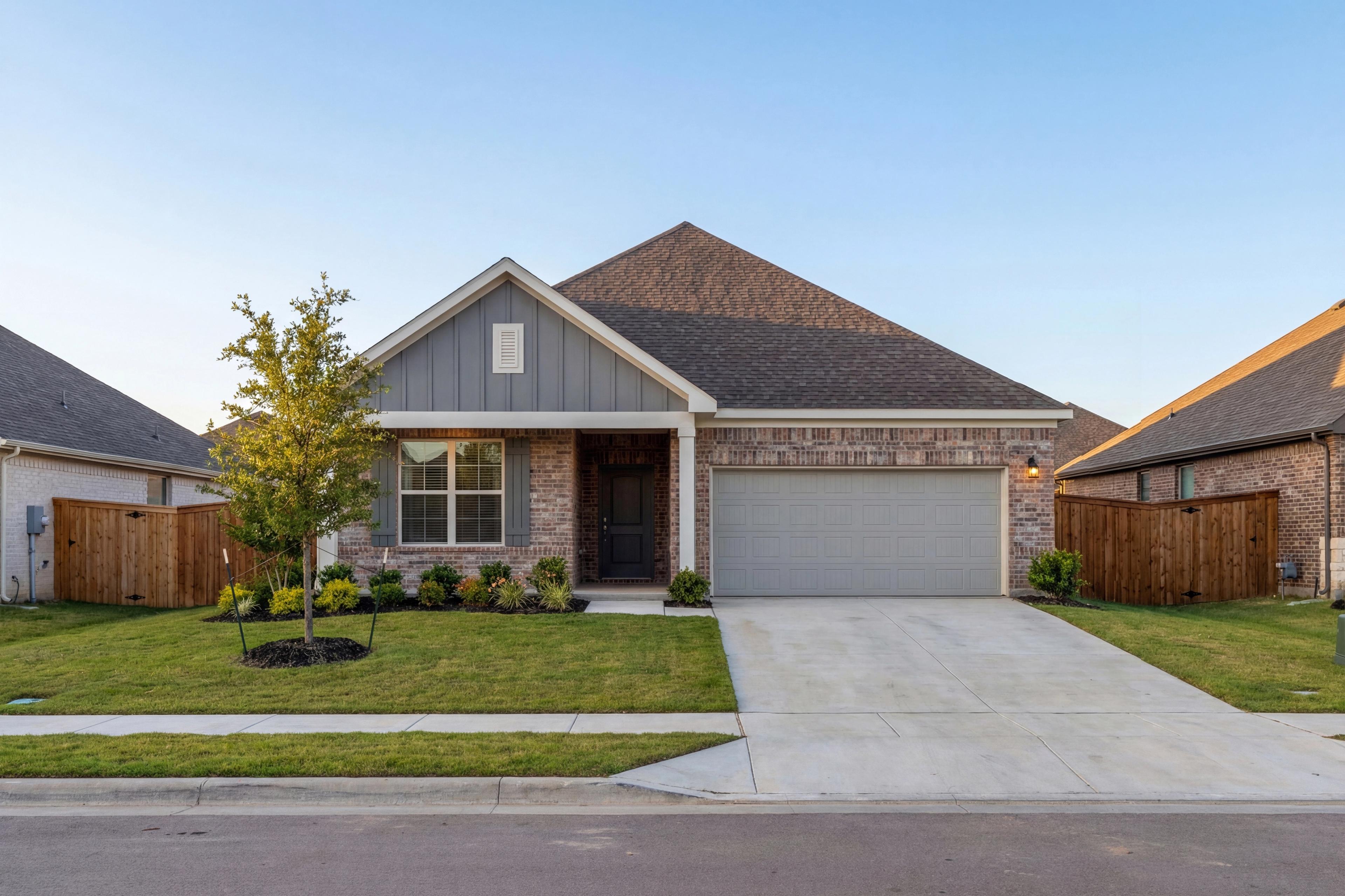 Modern single-story Everett home elevation featuring brick facade, gray siding, peaked roof, 2-car garage, and landscaped front yard