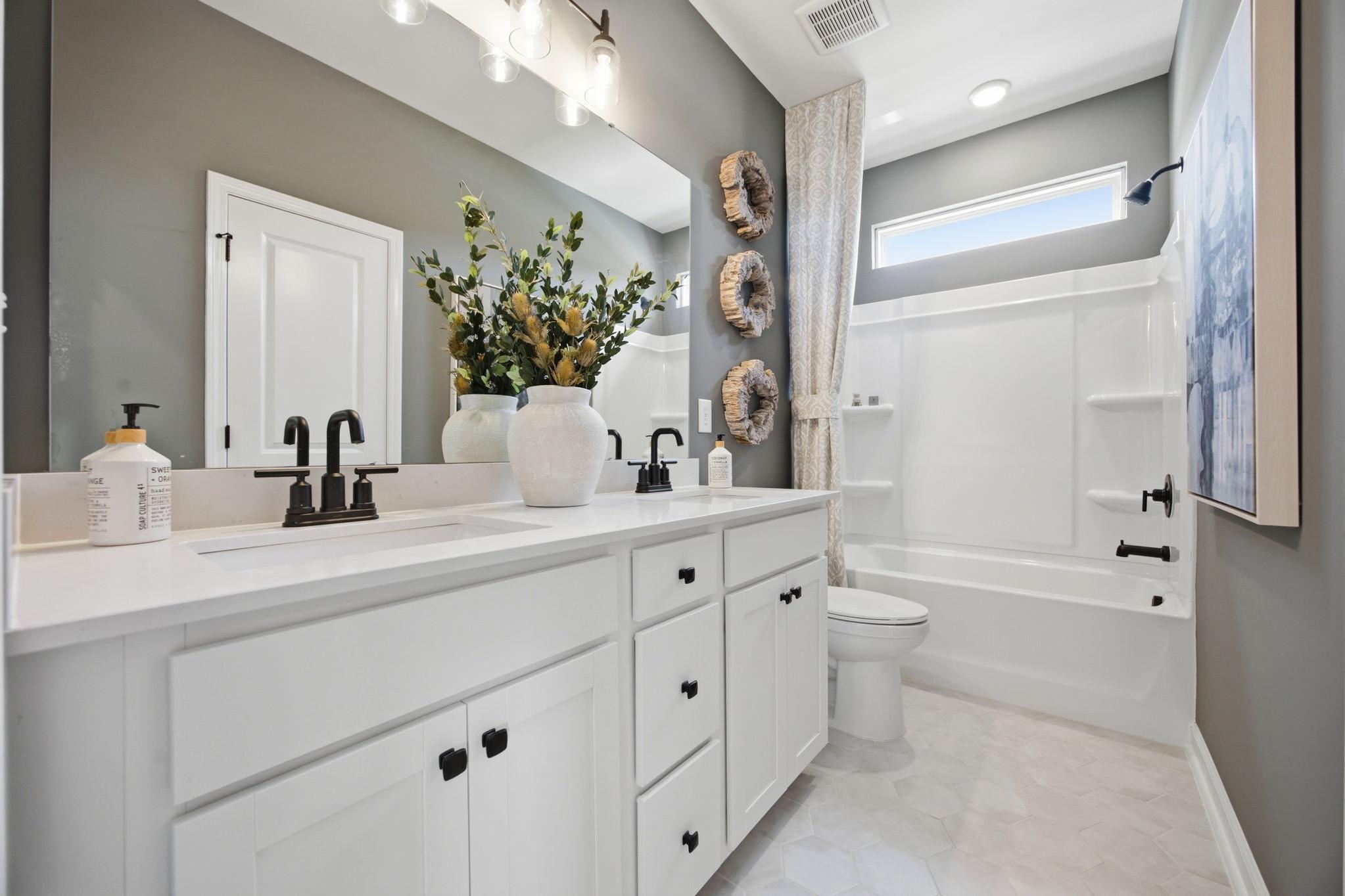 Spacious modern bathroom at Forestville Yard in Knightdale NC with white double vanity, gray walls, and hexagon tile floor