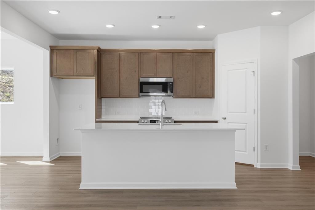Kitchen with large white island, wood cabinets, and microwave in The Russell B floor plan by Davidson Homes in Canton, Georgia