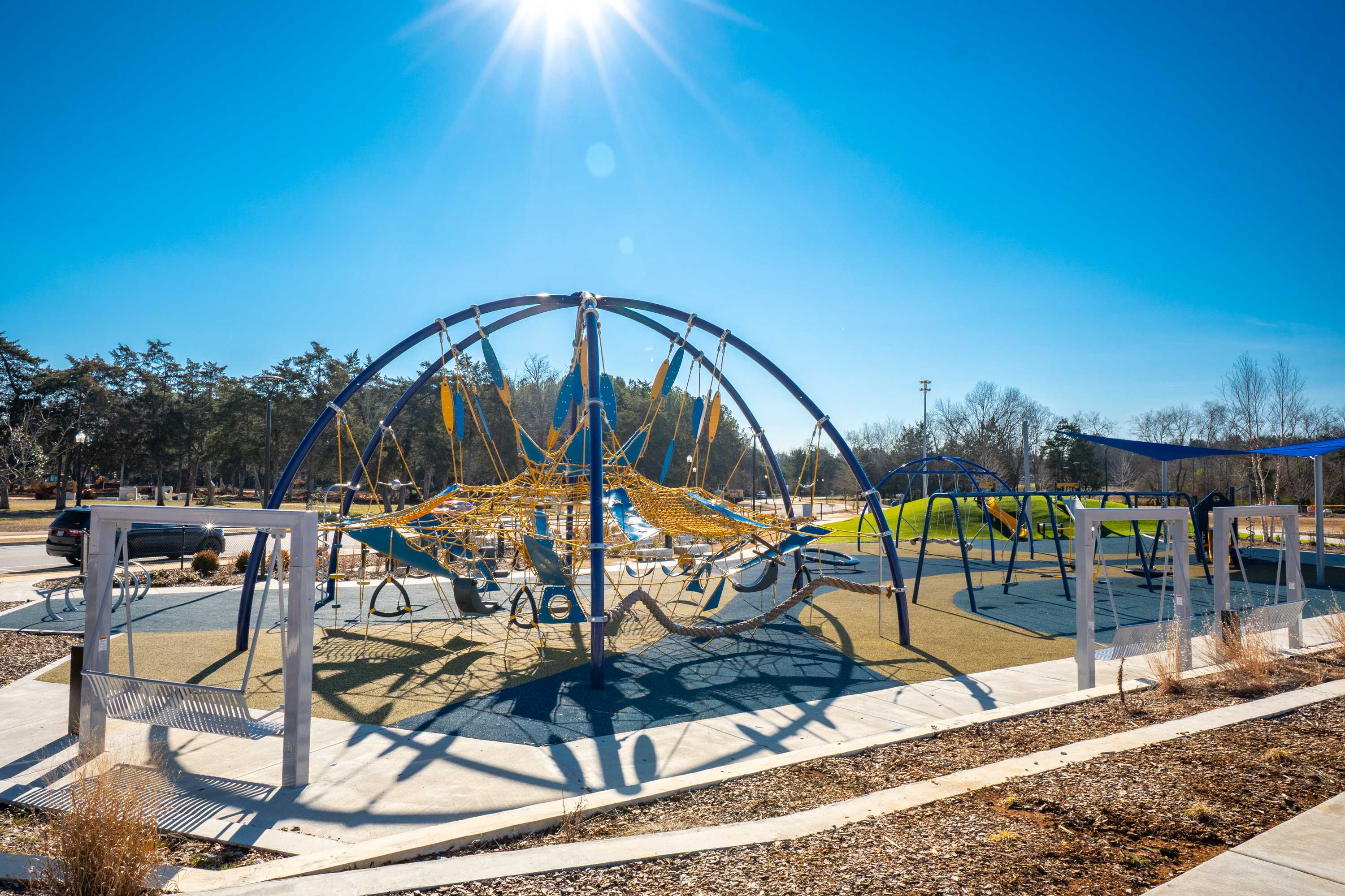 Vibrant playground at Jaguar Hills in Huntsville Alabama with colorful climbing nets swings and sunny blue skies