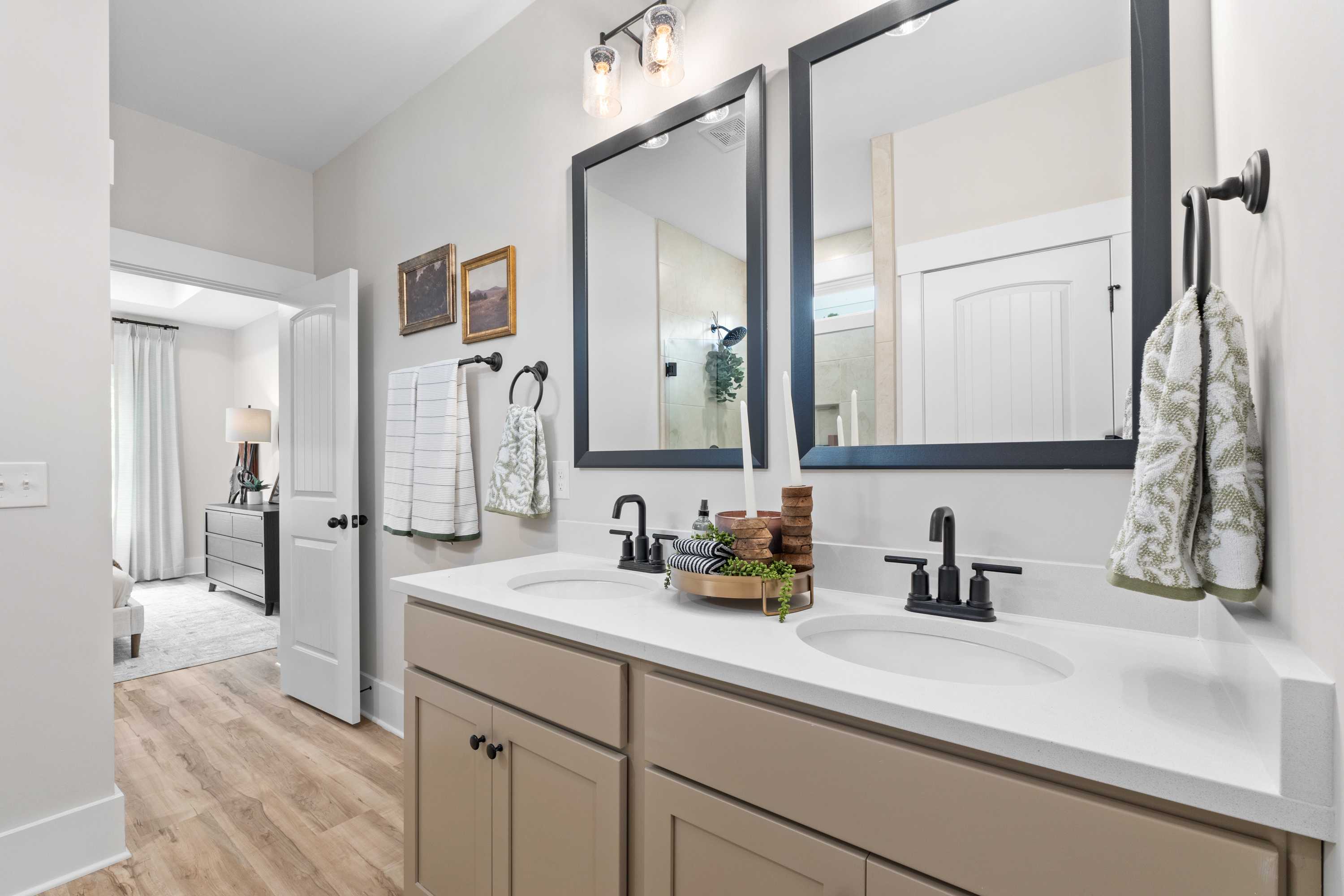 Spacious primary bathroom at Spragins Cove in Huntsville AL with double vanity, beige cabinets, large mirrors, and hardwood floors