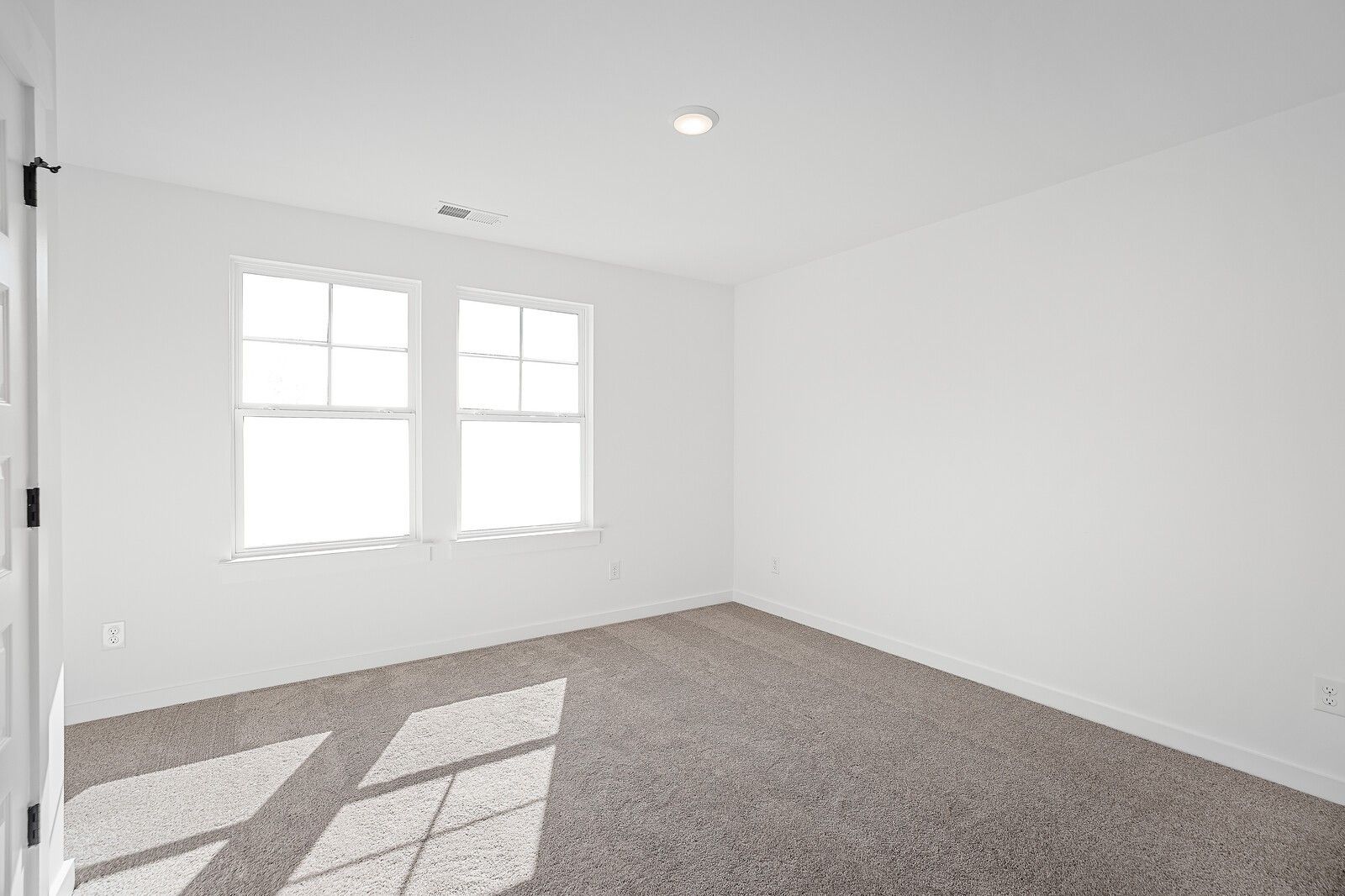 Bright empty bedroom with white walls, double windows, natural light, and beige carpet in The Logan C, Gallatin, TN