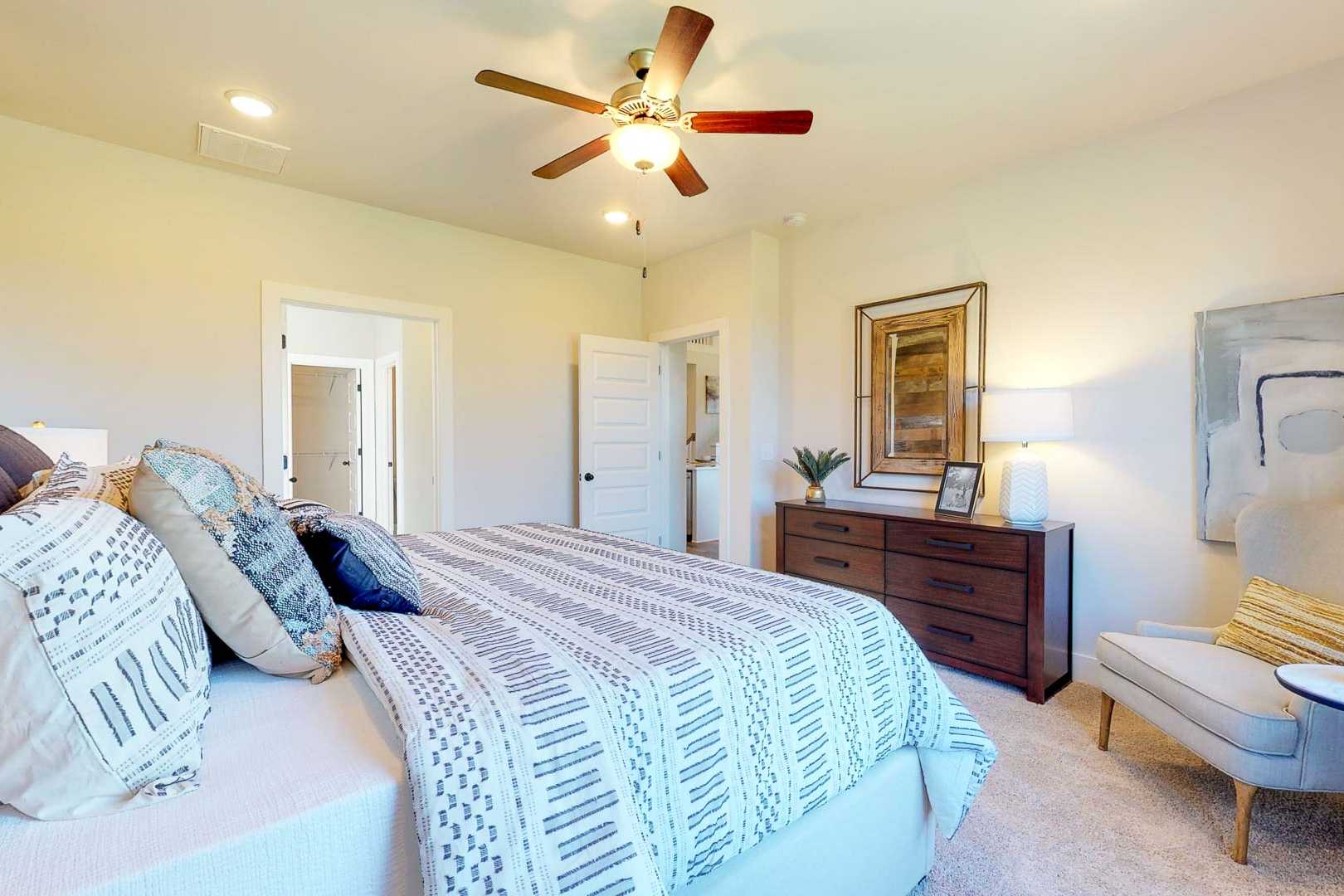 Spacious primary bedroom at Liberty Creek in Gallatin TN with king bed, ceiling fan, accent wall, and modern artwork