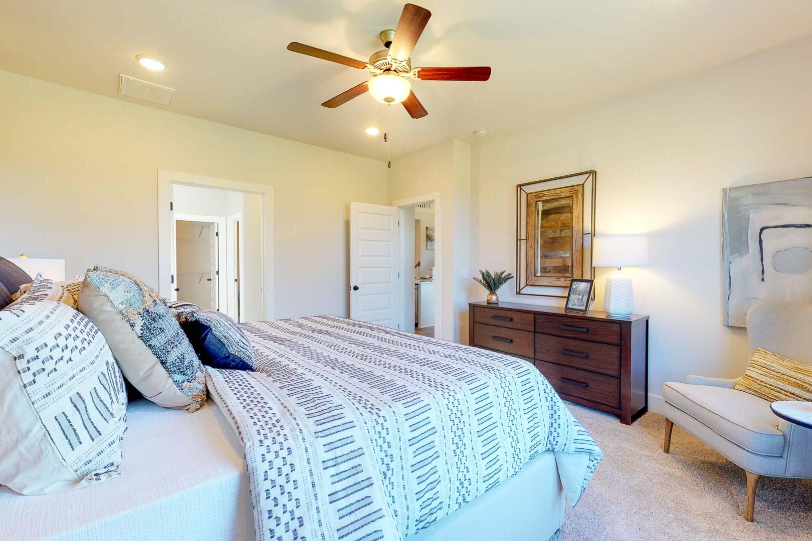 Spacious primary bedroom at Liberty Creek in Gallatin TN with king bed, ceiling fan, accent wall, and modern artwork