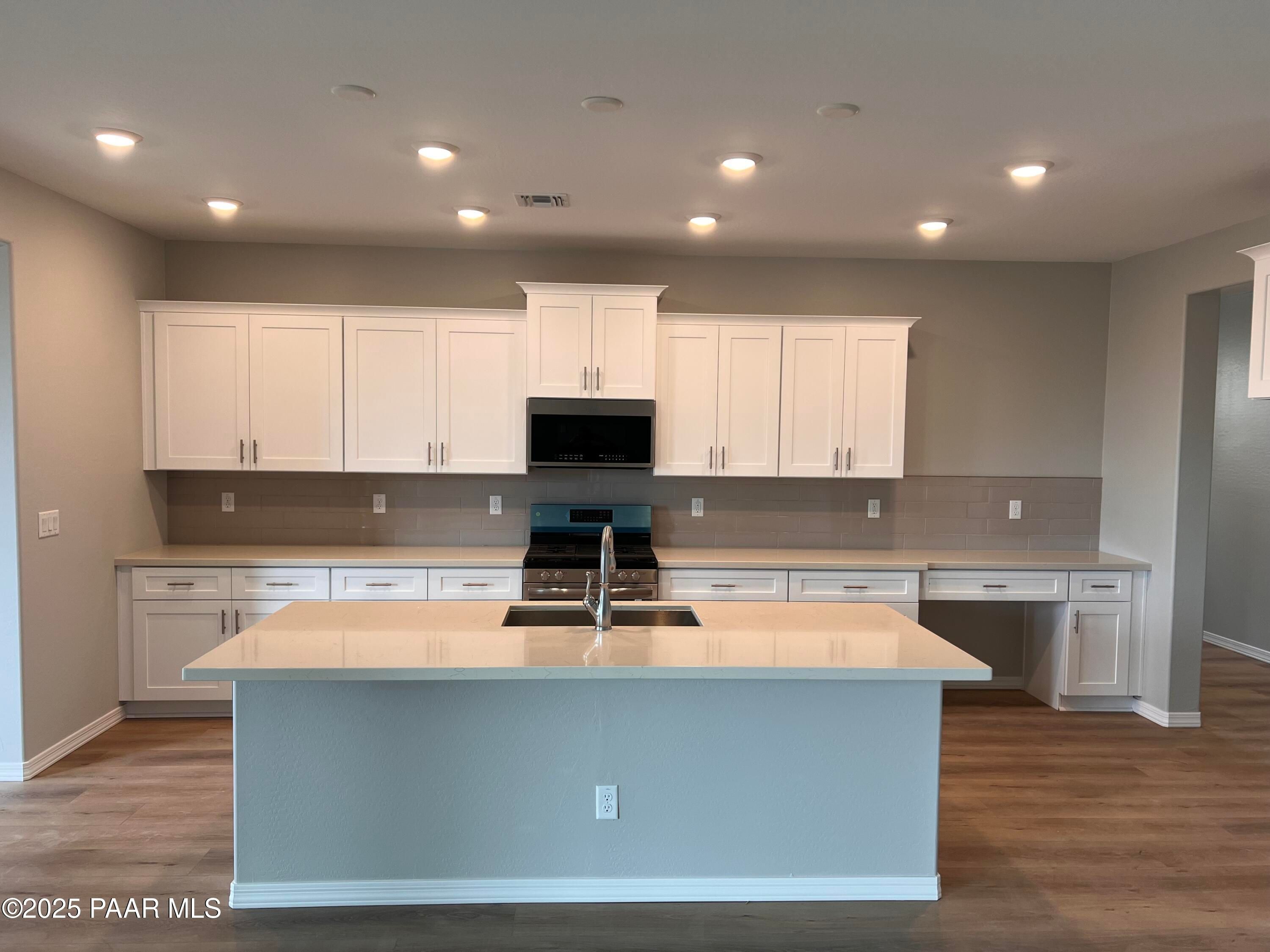 Modern white shaker kitchen with large granite island, stainless steel appliances, subway tile backsplash in Davidson Homes The Inspiration B, Prescott Valley, AZ