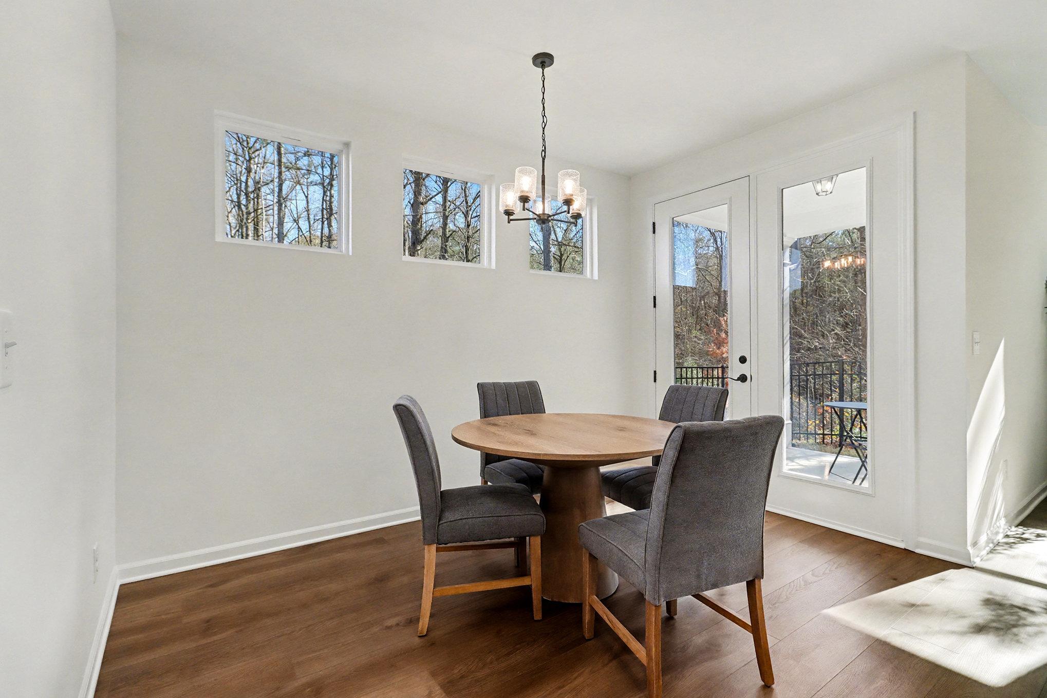 Bright dining room with chandelier, French doors to wooded view, hardwood floors in The Daphne B, Loganville GA