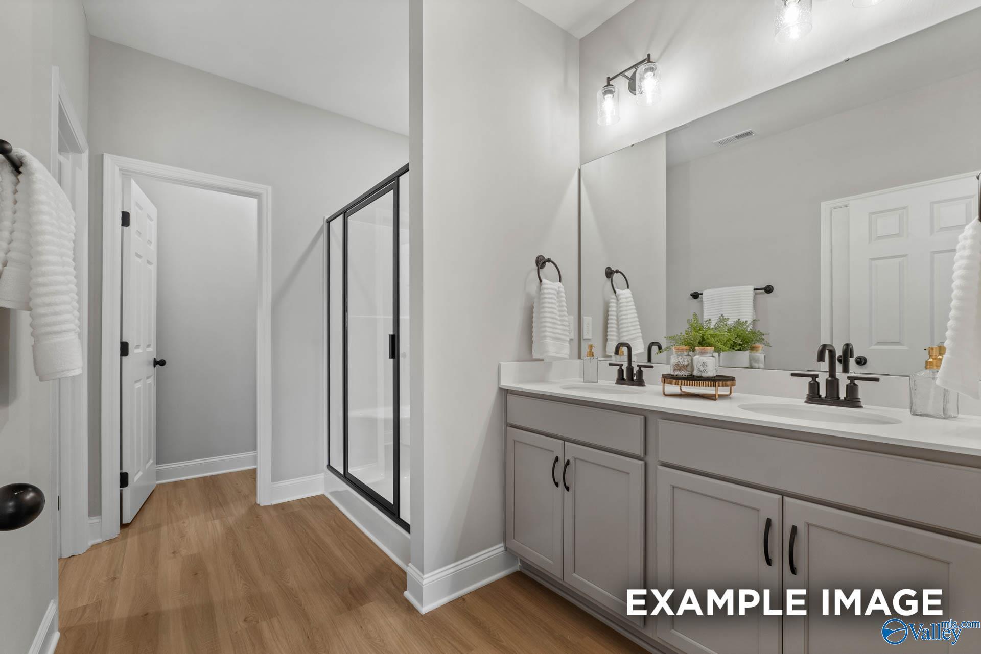 Modern bathroom with double vanity, glass shower, gray cabinets in Davidson Homes The Daphne C, Owens Cross Roads, Alabama