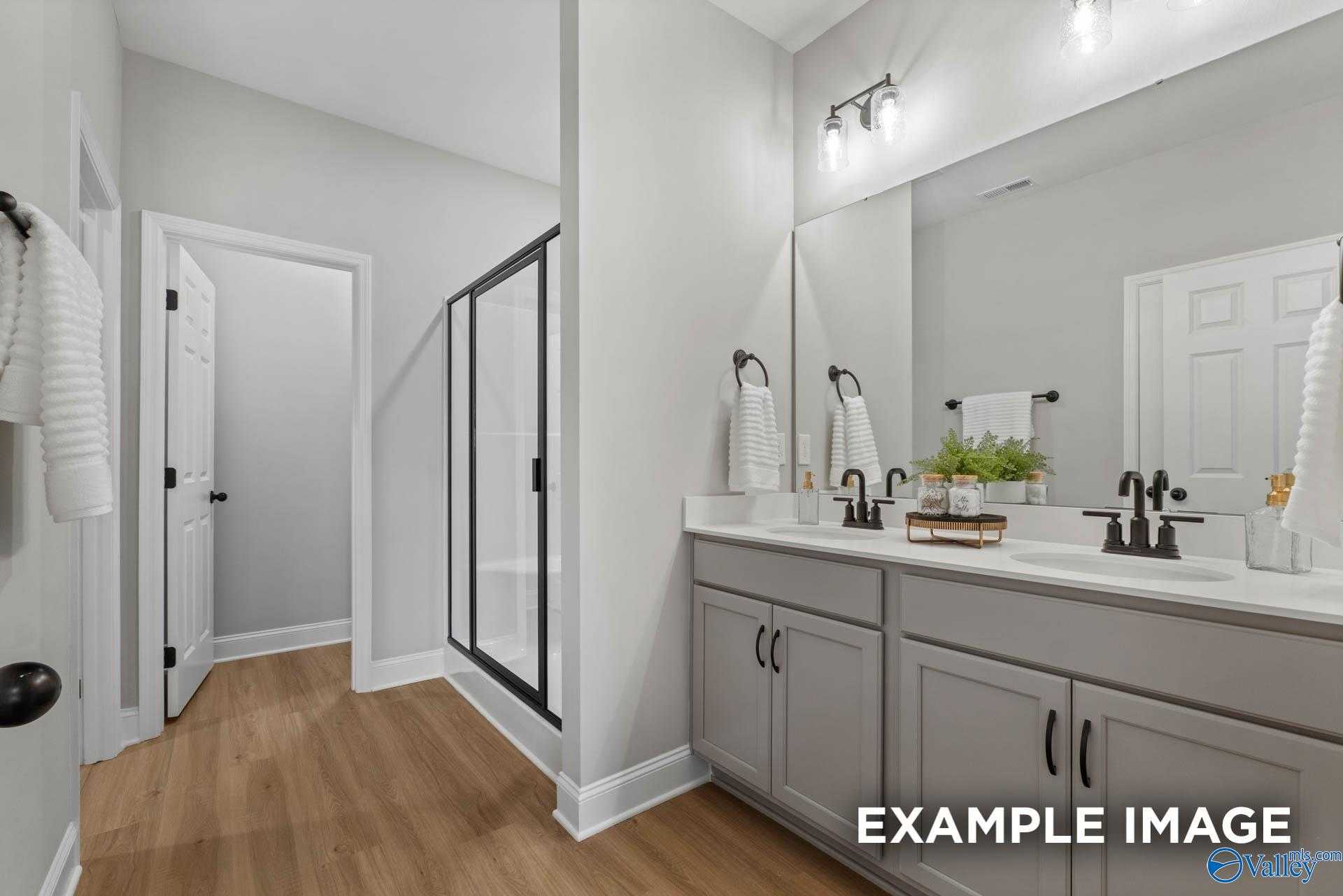 Modern bathroom with double vanity, glass shower, gray cabinets in Davidson Homes The Daphne C, Owens Cross Roads, Alabama