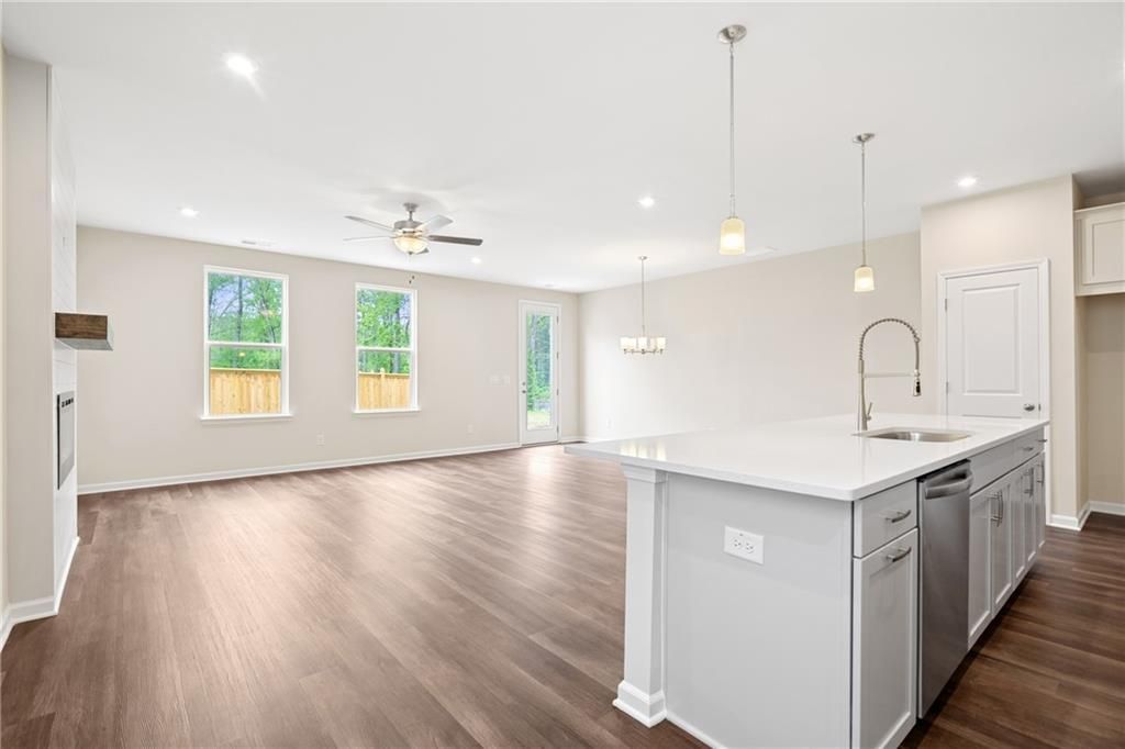 Open-concept kitchen-living area with white island, stainless appliances, hardwood floors, and French doors in Davidson Homes The Cary B, Kennesaw, GA
