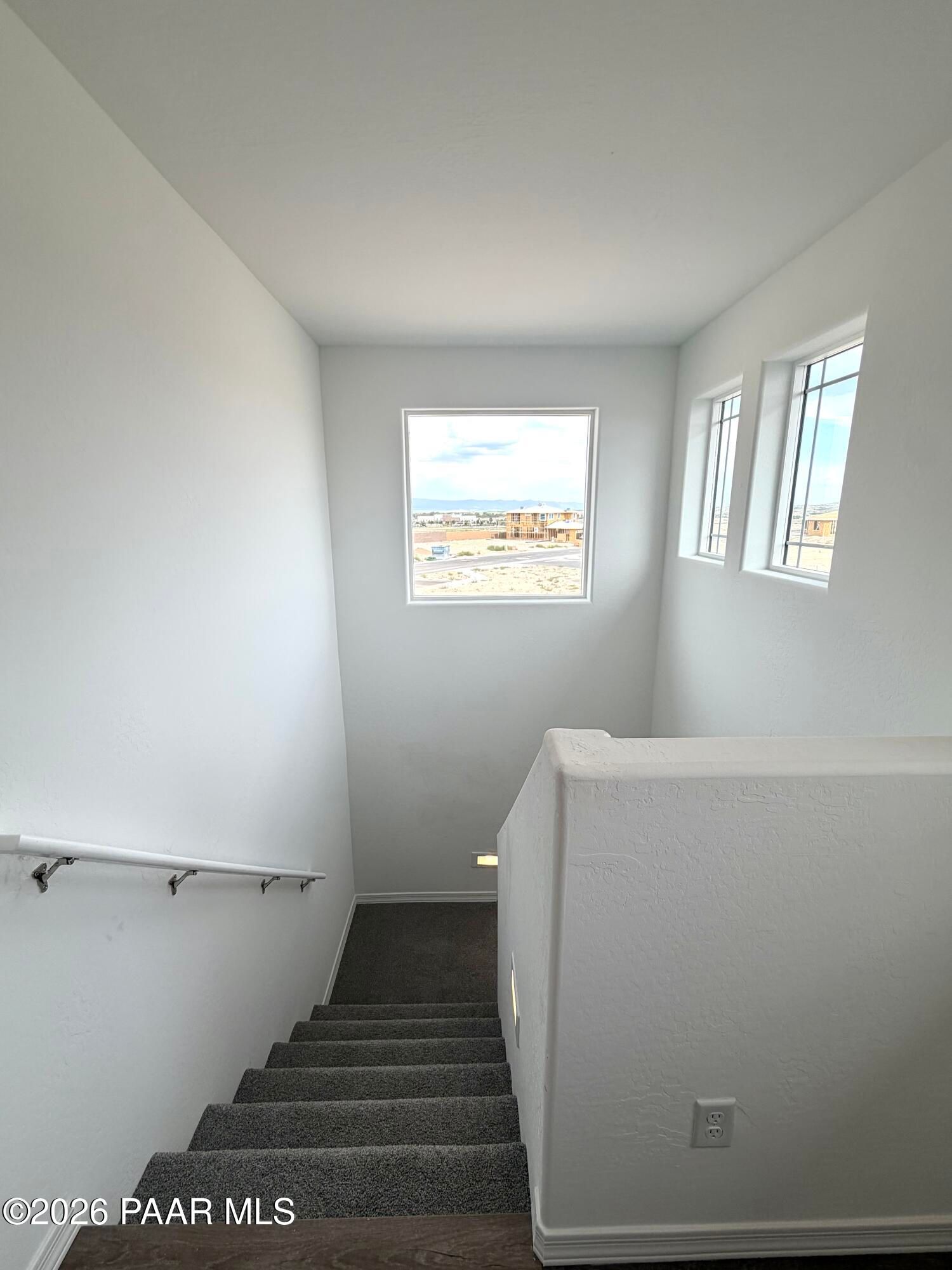 Staircase with plush carpet and large windows in The Raleigh A floor plan at South Ranch, Prescott, Arizona.