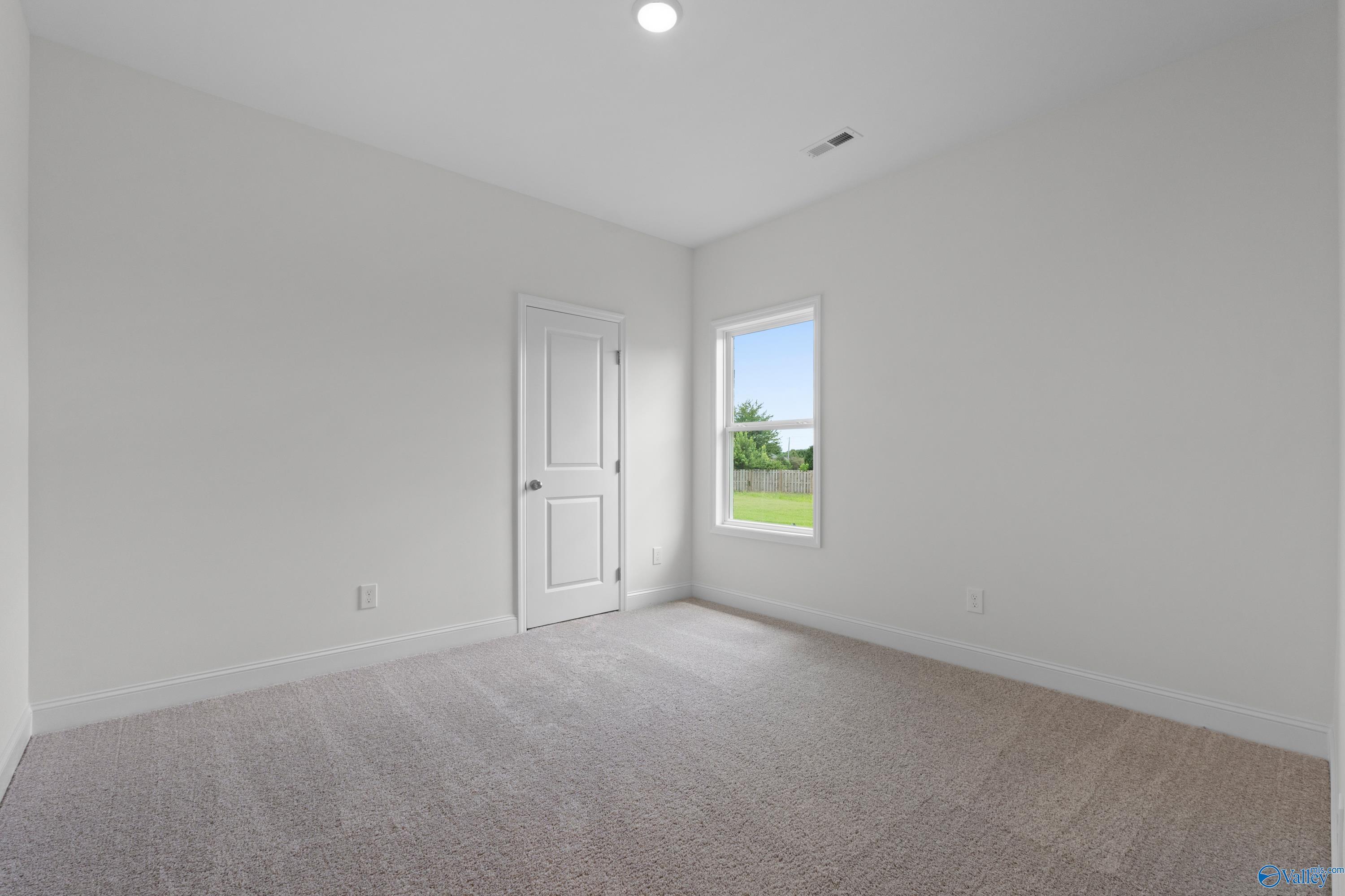 Bright, neutral-toned bedroom with plush carpeting in The Everett B floor plan by Davidson Homes in Athens, Alabama.
