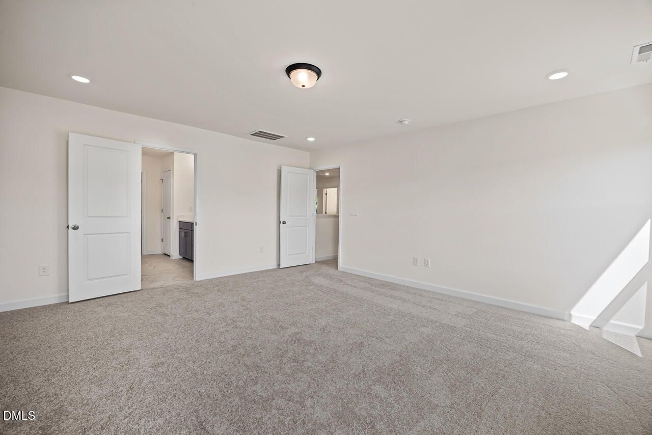 Spacious carpeted owner's bedroom with double doors leading to bath in Davidson Homes Hickory II B, Lillington NC