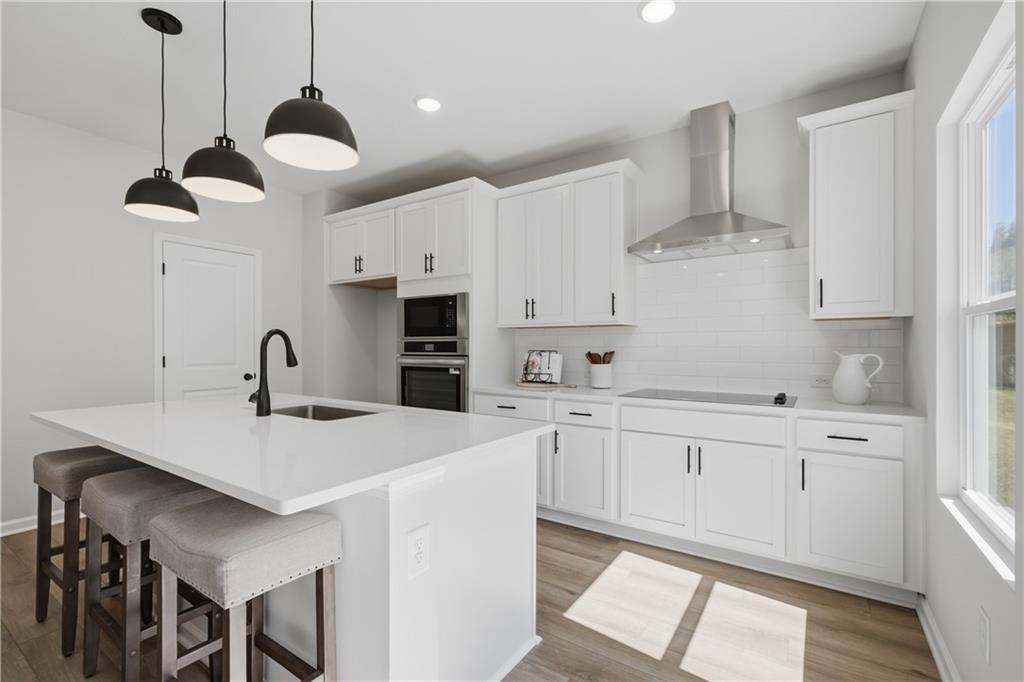Bright white kitchen with large island, pendant lighting, and stainless appliances in Davidson Homes Hartwell C plan, Canton, GA