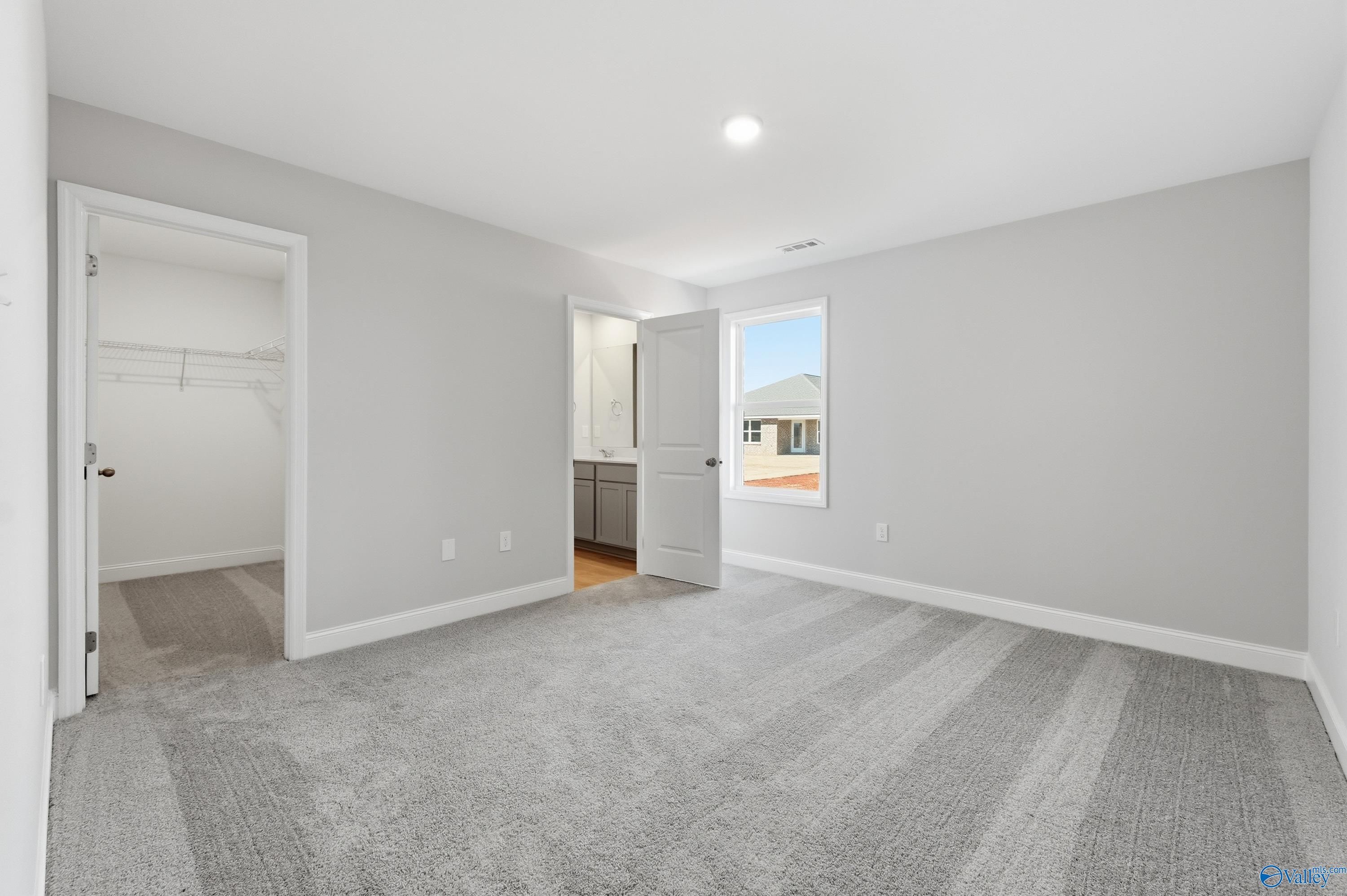 Spacious secondary bedroom with gray walls, carpet flooring, walk-in closet, and en-suite bath in Davidson Homes The Butler, New Market, AL
