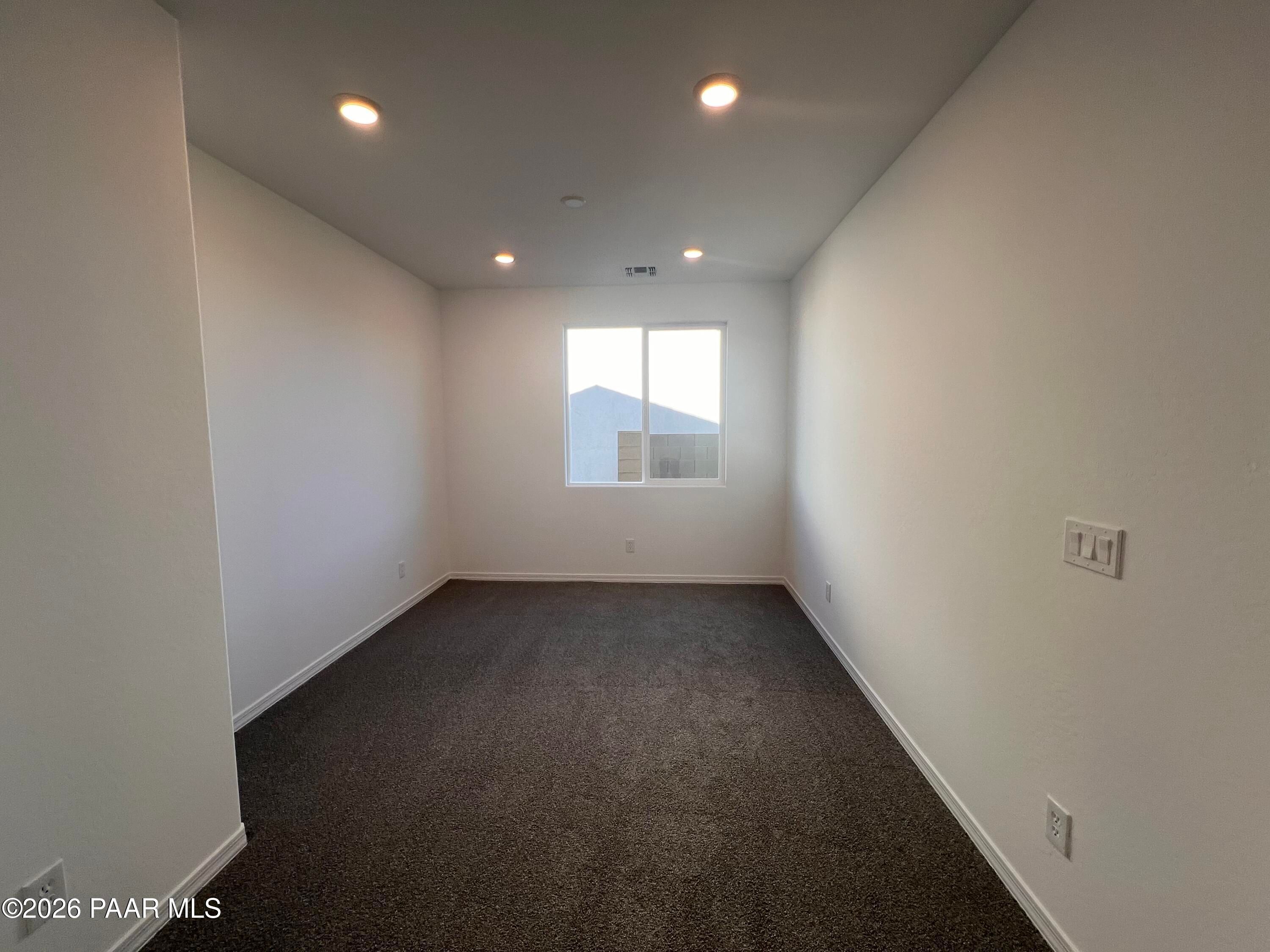 Spacious empty bedroom with white walls, brown carpet, large window and recessed lights in Davidson Homes Sunrise II A, Prescott AZ