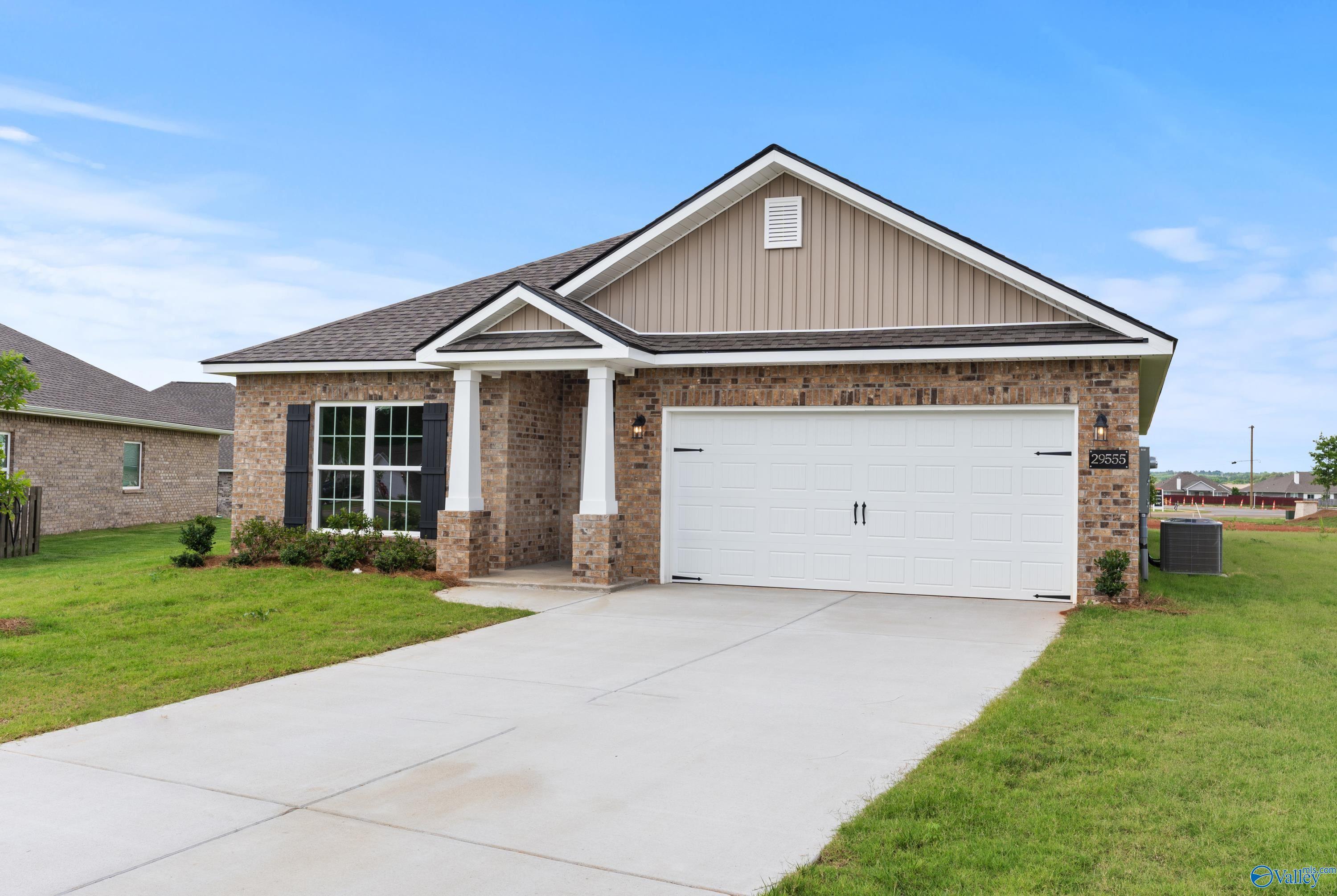 Modern single-story 4-bedroom home with 2-car garage, brick accents, columned porch, and lush lawn in Creekside, Harvest, Alabama