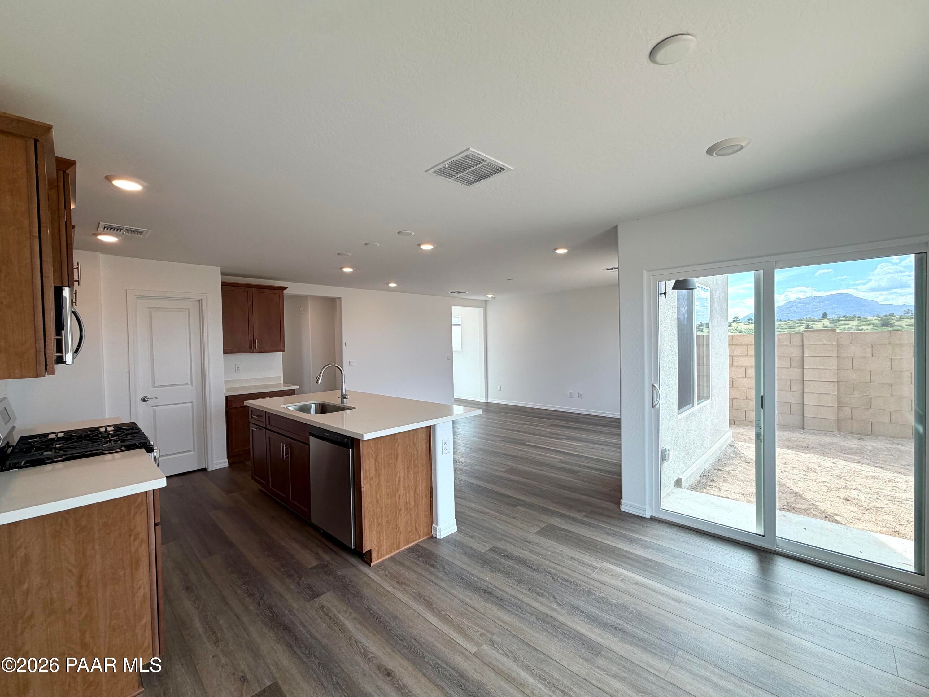 Open-concept kitchen with island and wood flooring in The Raleigh A floor plan at South Ranch, Prescott, Arizona.