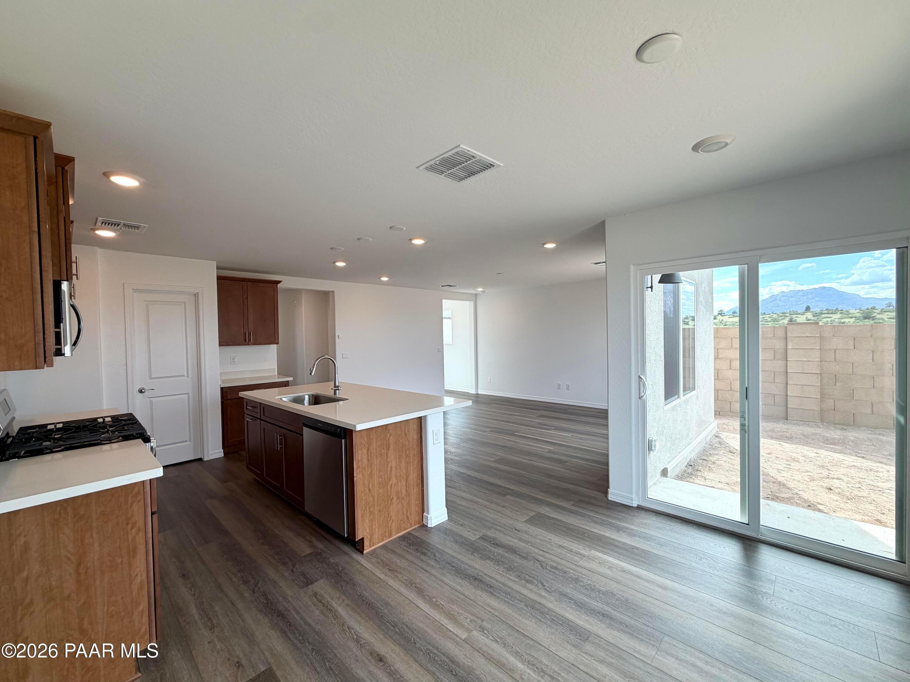 Open-concept kitchen with island and wood flooring in The Raleigh A floor plan at South Ranch, Prescott, Arizona.