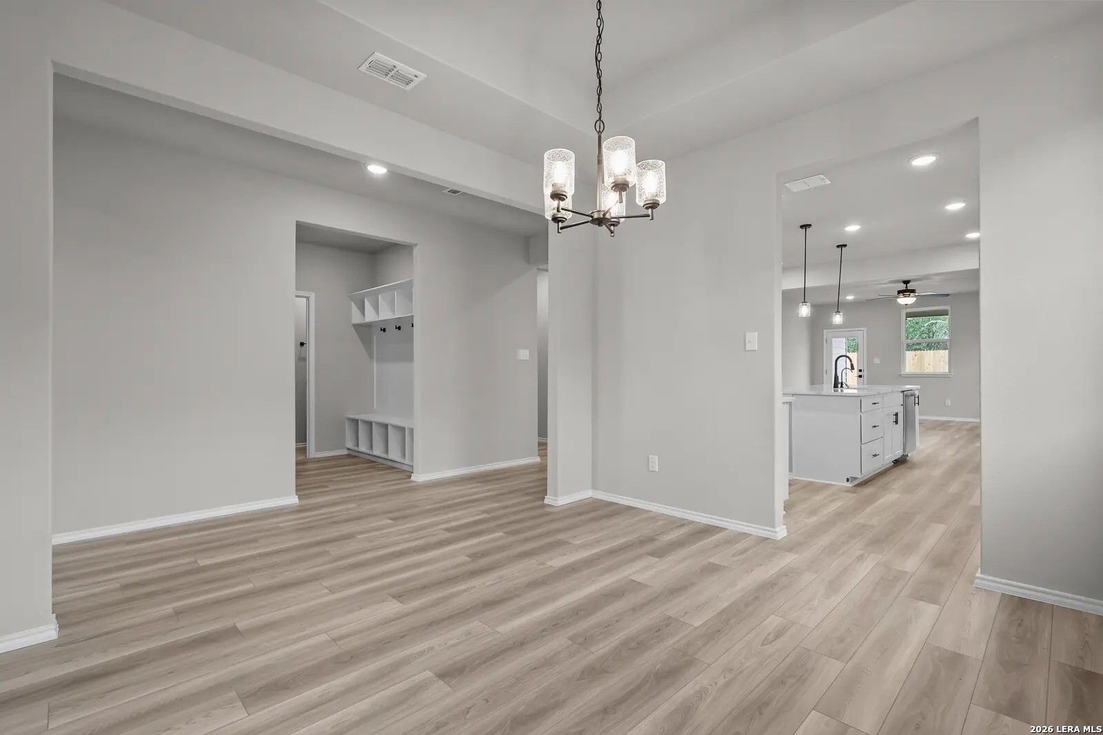 Dining area with chandelier, mudroom, and view into kitchen in The Glenwood E floor plan at Comanche Ridge, San Antonio.