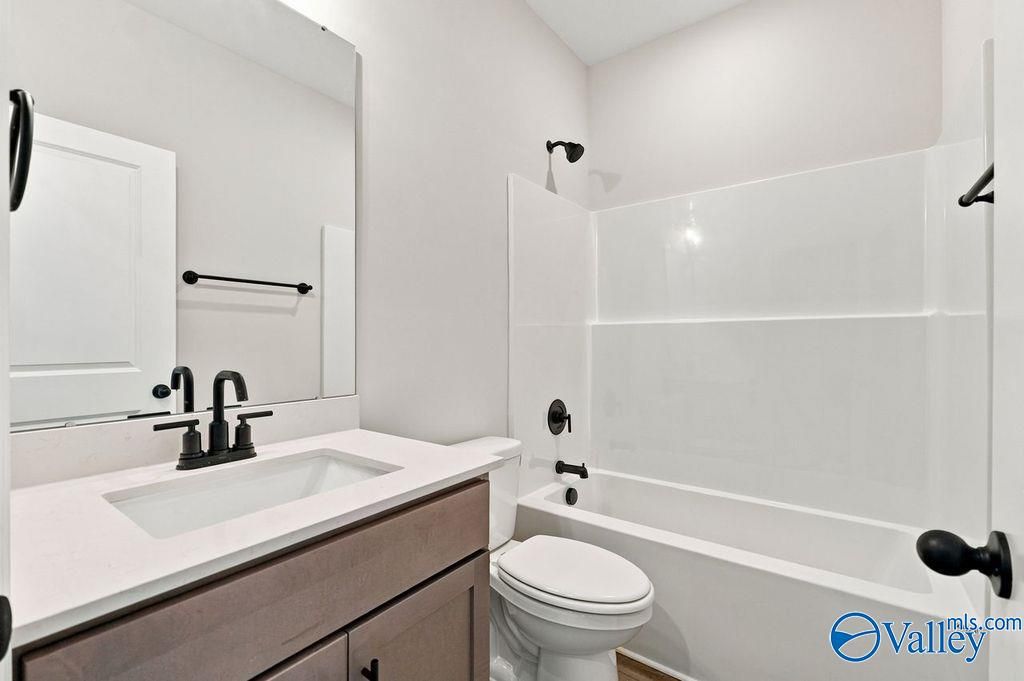 Modern bathroom with white vanity, quartz countertop, and tub-shower combo in The Camilla C floor plan, Hartselle, Alabama.