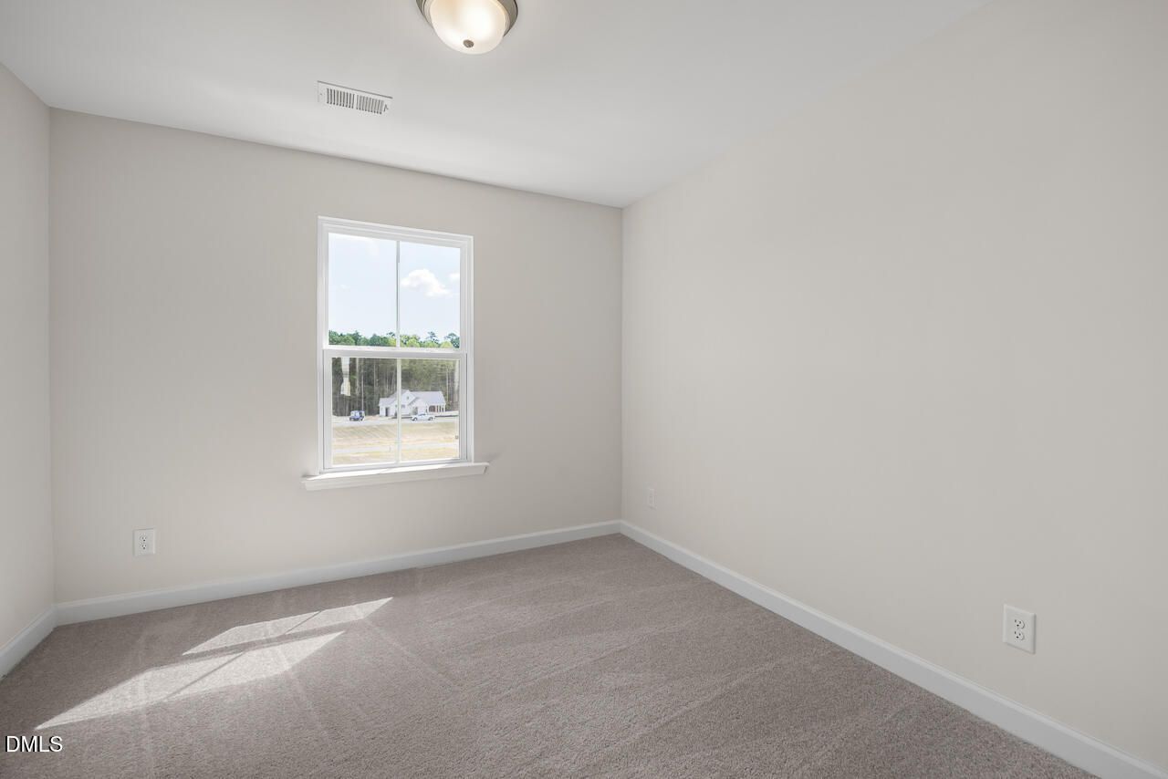 Bright empty bedroom with carpet and window overlooking trees in Davidson Homes' Mitchell plan, Knightdale, NC townhome