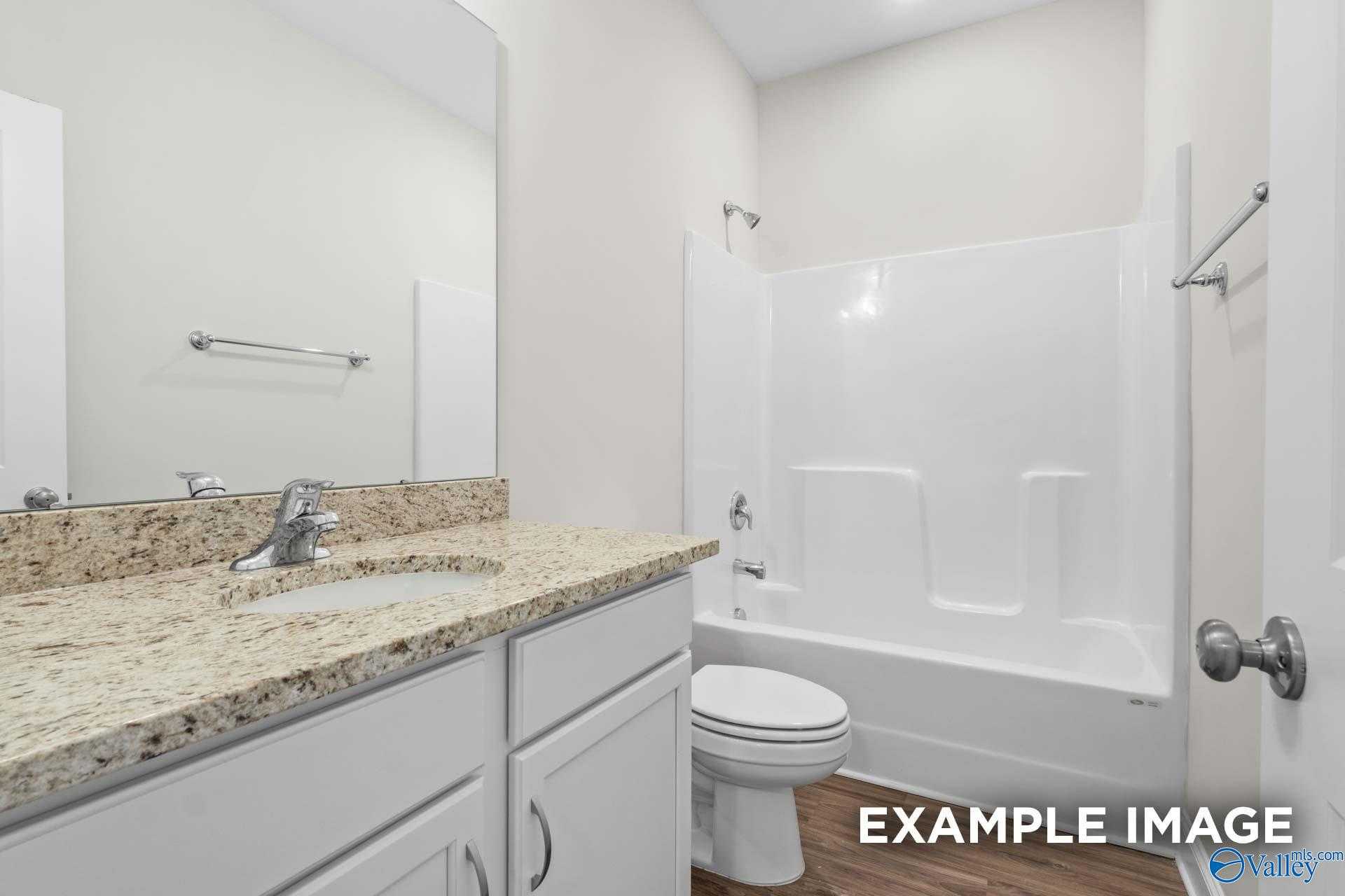 Modern bathroom featuring granite vanity, white tub-shower combo, and tiled walls in Davidson Homes The Franklin, Meridianville, Alabama