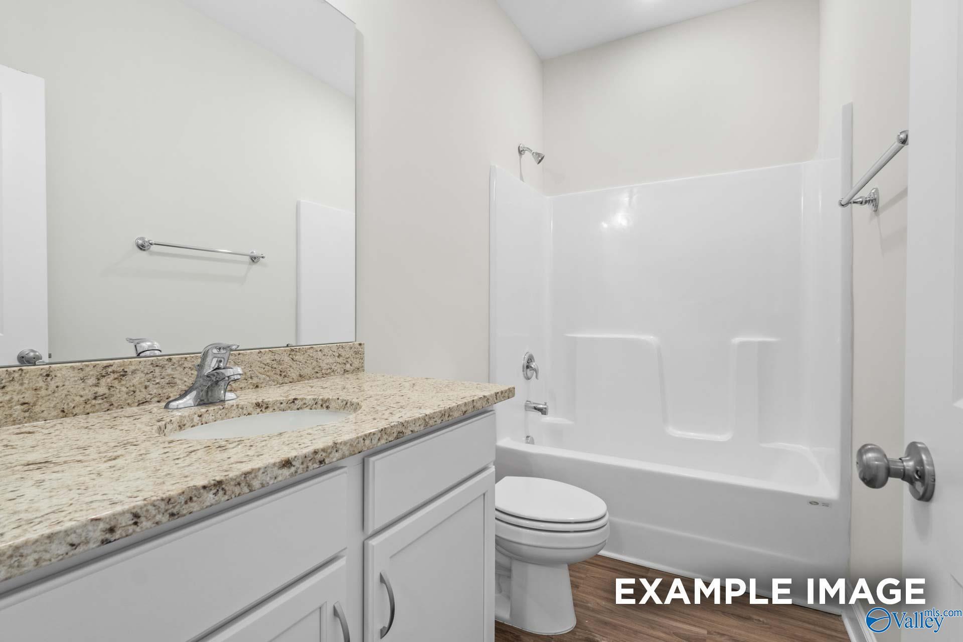 Modern bathroom with granite vanity, white cabinetry, and shower-tub combo in The Franklin floor plan, Hazel Green, AL.