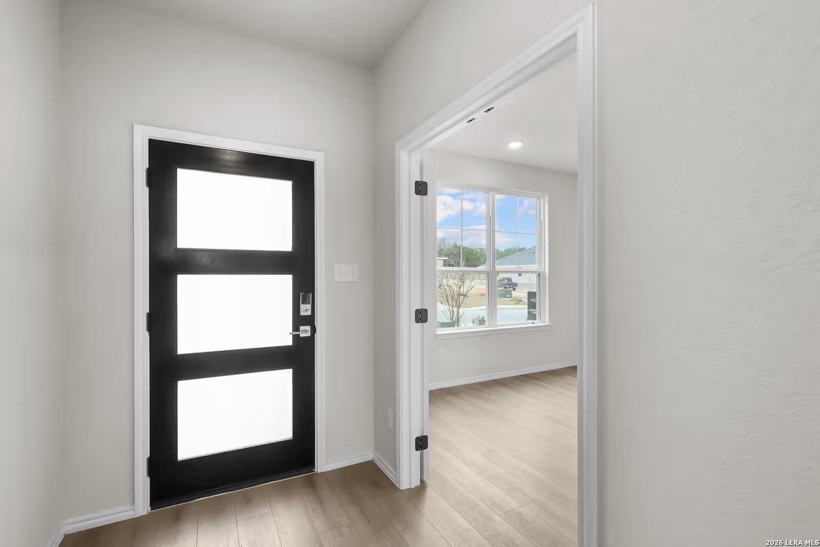 Modern black front door with frosted glass panels in bright foyer of Davidson Homes The Sequoia C in Comanche Ridge, San Antonio, Texas
