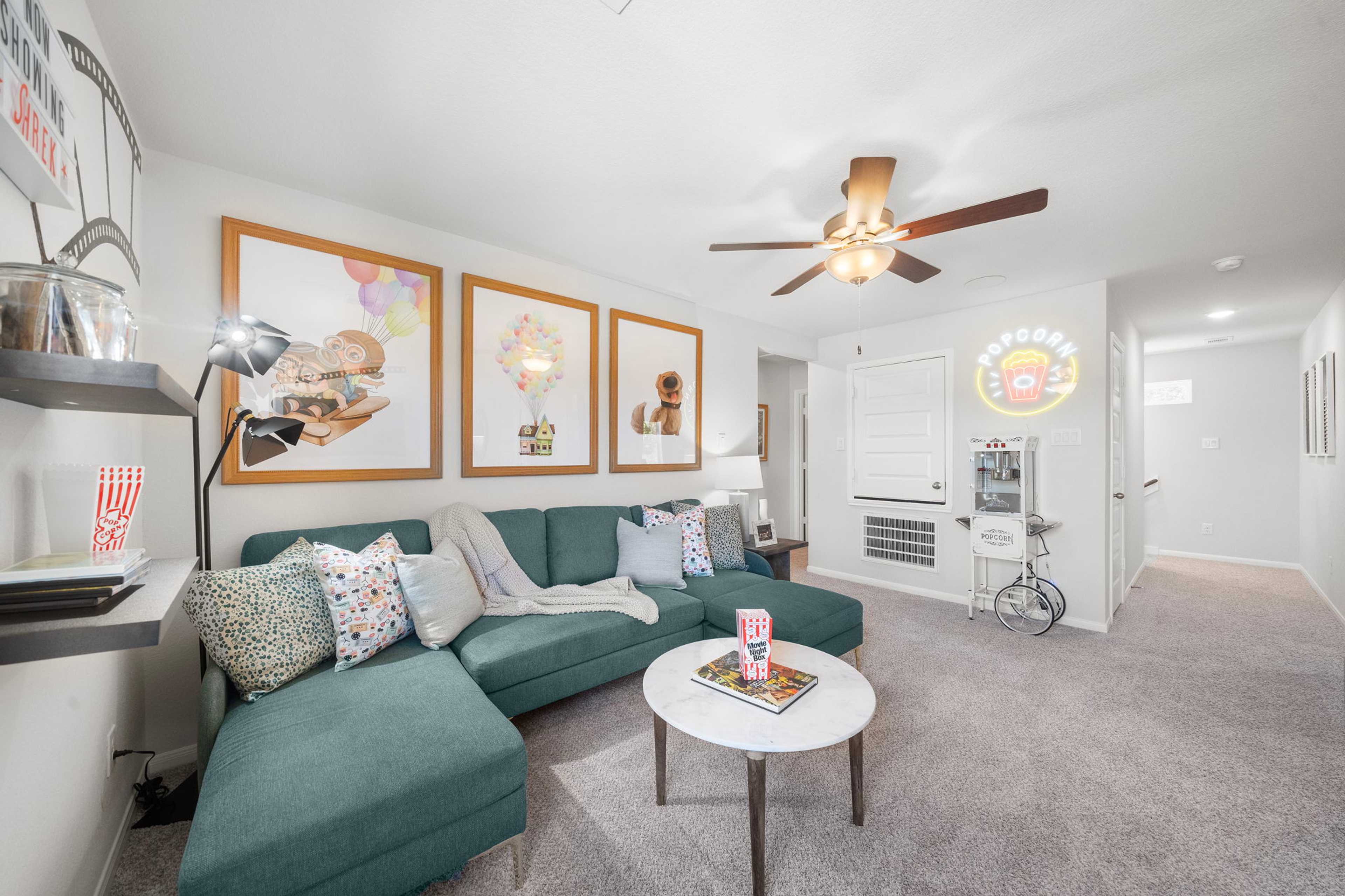 Cozy media room at Caney Creek Place in Conroe TX with teal sectional sofa, balloon posters, and popcorn machine