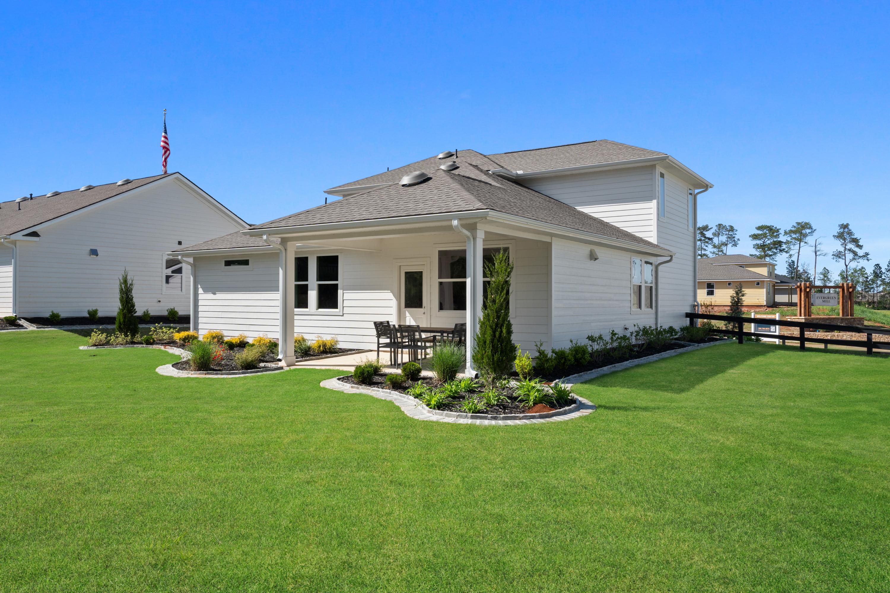 Modern home backyard patio at Evergreen Mill in Madison, Alabama with covered seating, landscaped plants, and lush green lawn
