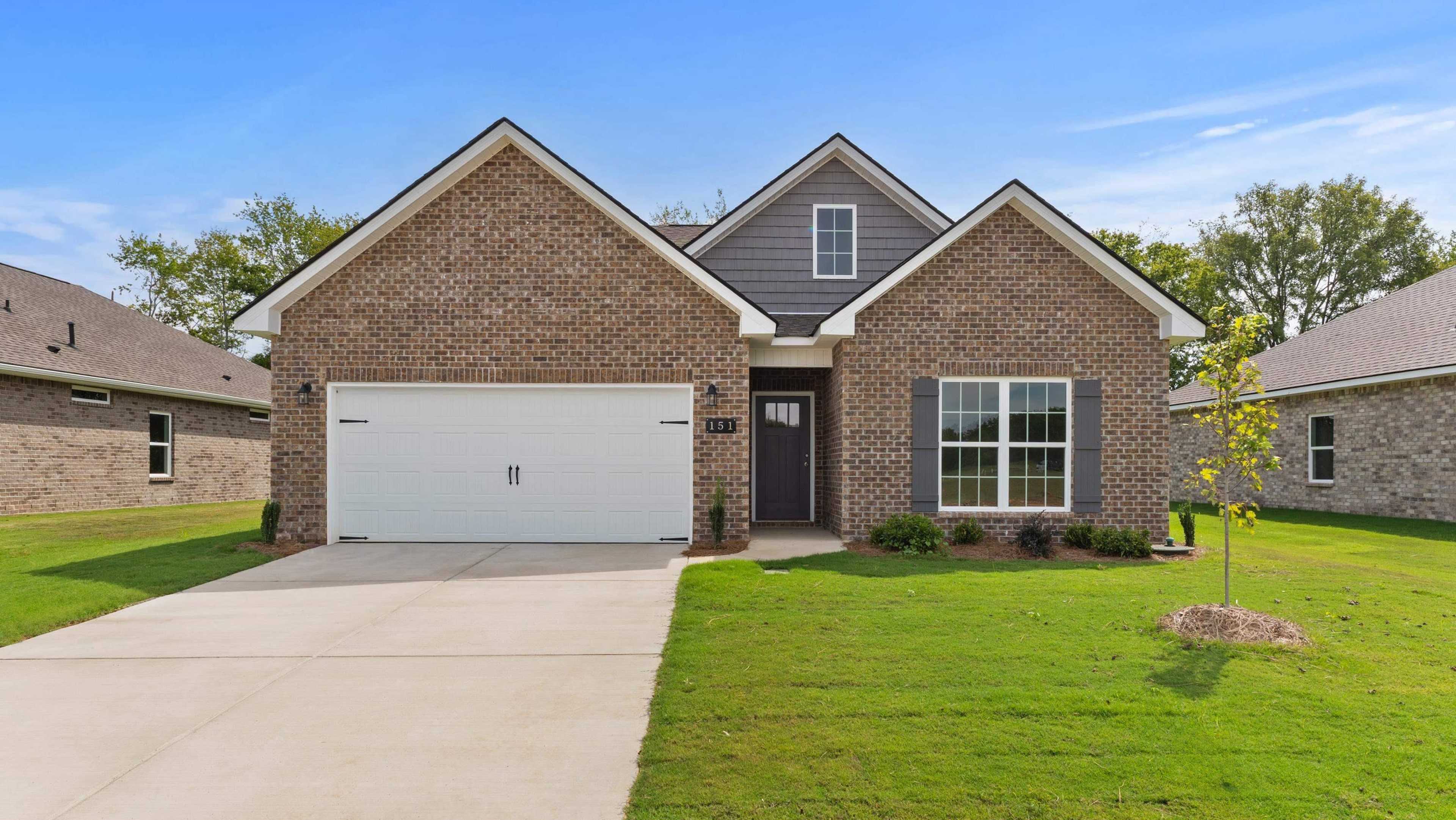 Modern brick home at Davidson Homes open house, 151 Ivy Vine Drive, featuring gabled roof, garage, driveway, and lush green lawn