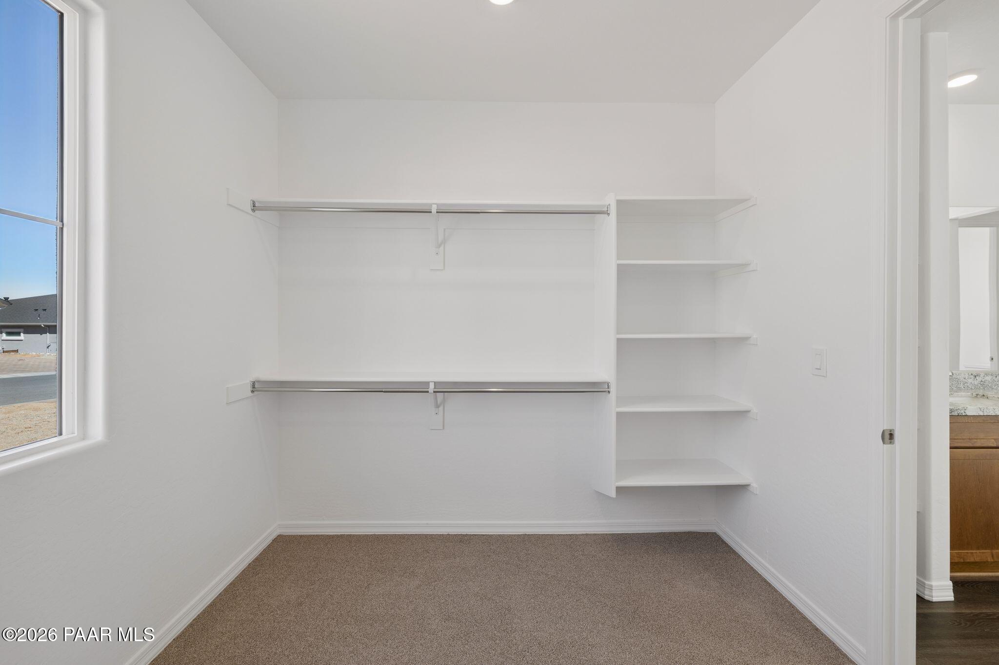 Spacious walk-in closet with built-in white shelves and hanging rods in master suite, Davidson Homes The Monarch A, Prescott Arizona