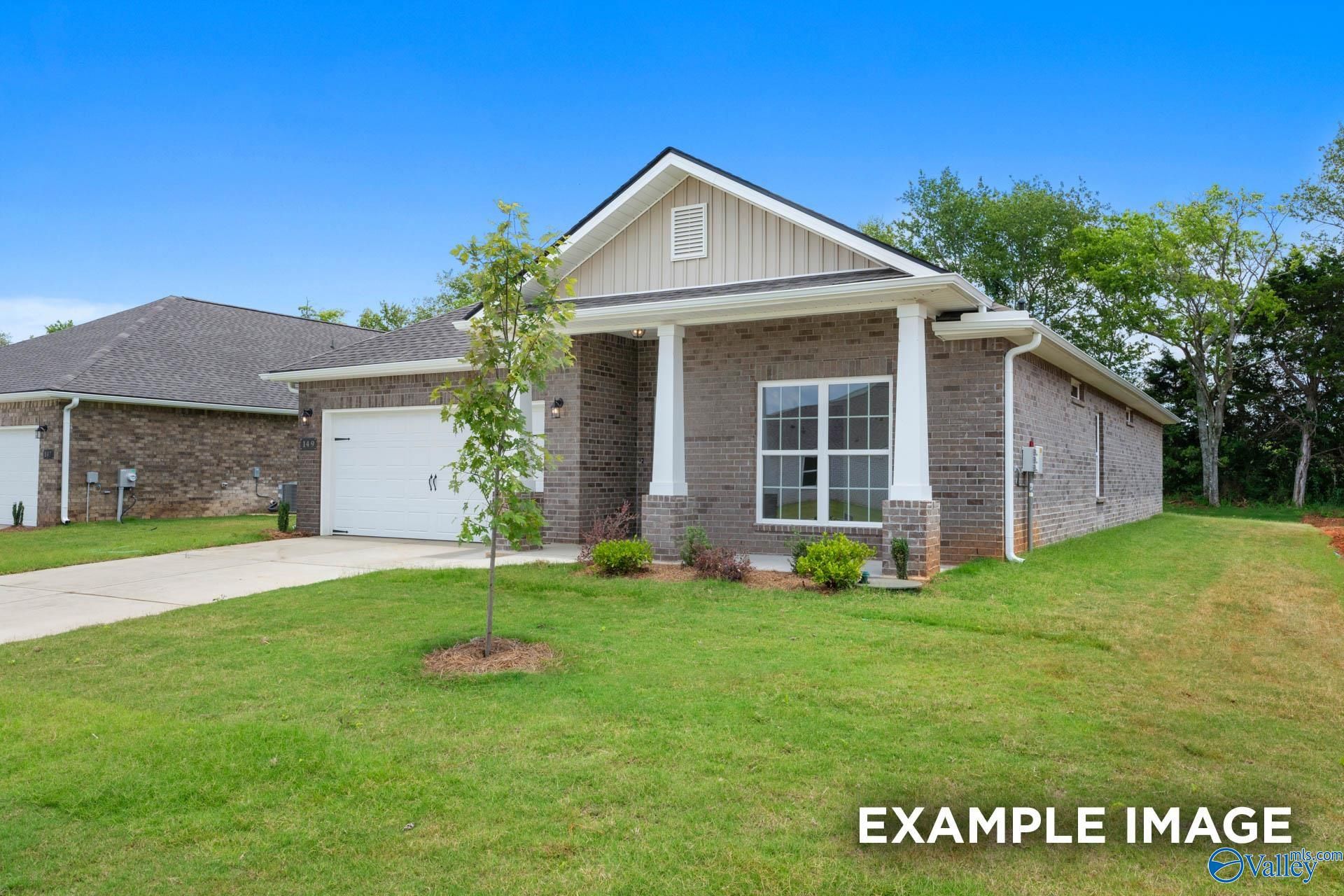 Single-story brick home with gabled roof, covered front porch, two-car garage, and landscaped yard in Carroll Green, Harvest, Alabama