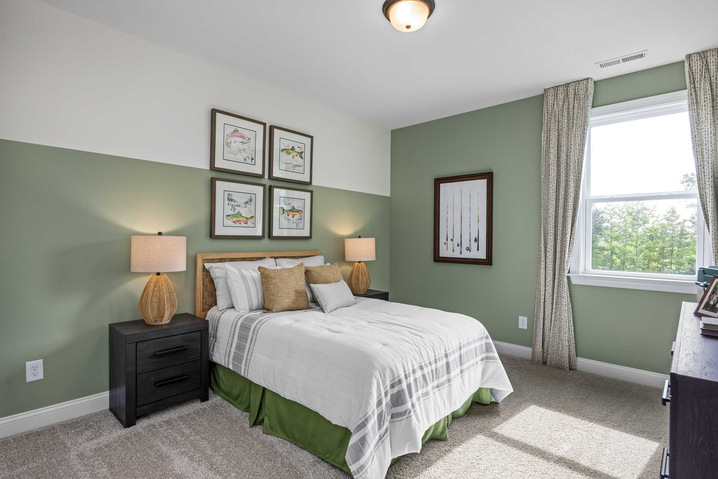 Cozy bedroom at Laneridge Estates in Raleigh NC with green accent wall, white bed, framed art, and window view