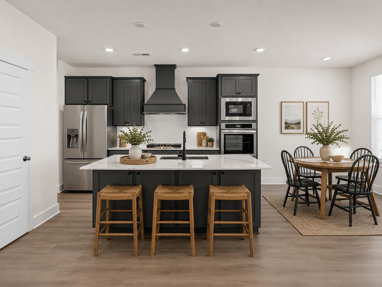 Modern kitchen with dark cabinetry, white countertops, and island seating in The Willow plan at Woods Crossing, Gallatin.