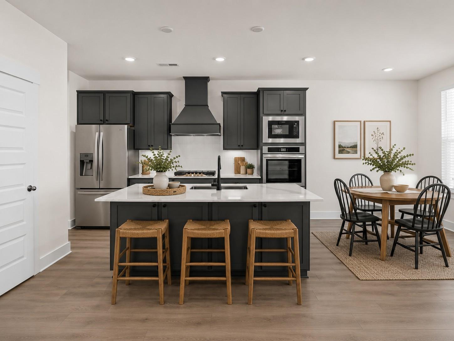 Modern kitchen with dark cabinetry, white countertops, and island seating in The Willow plan at Woods Crossing, Gallatin.