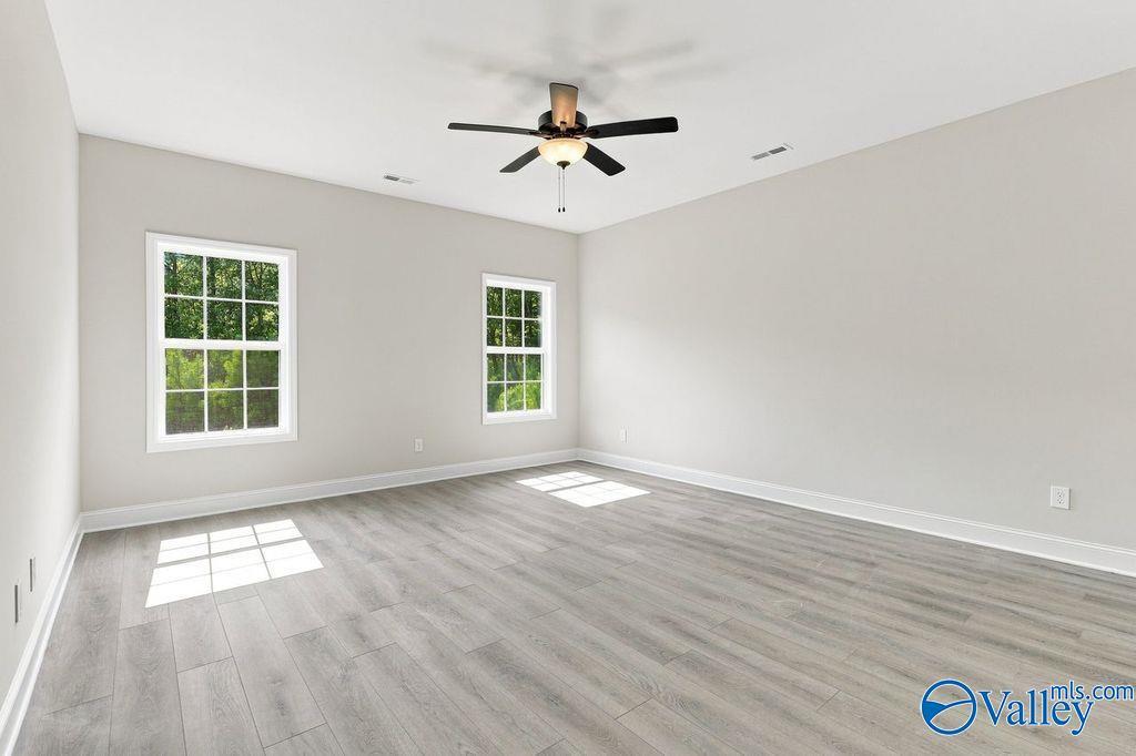 Bright empty bedroom with luxury vinyl plank flooring, ceiling fan, and dual windows in Davidson Homes Rockford plan, Hartselle AL