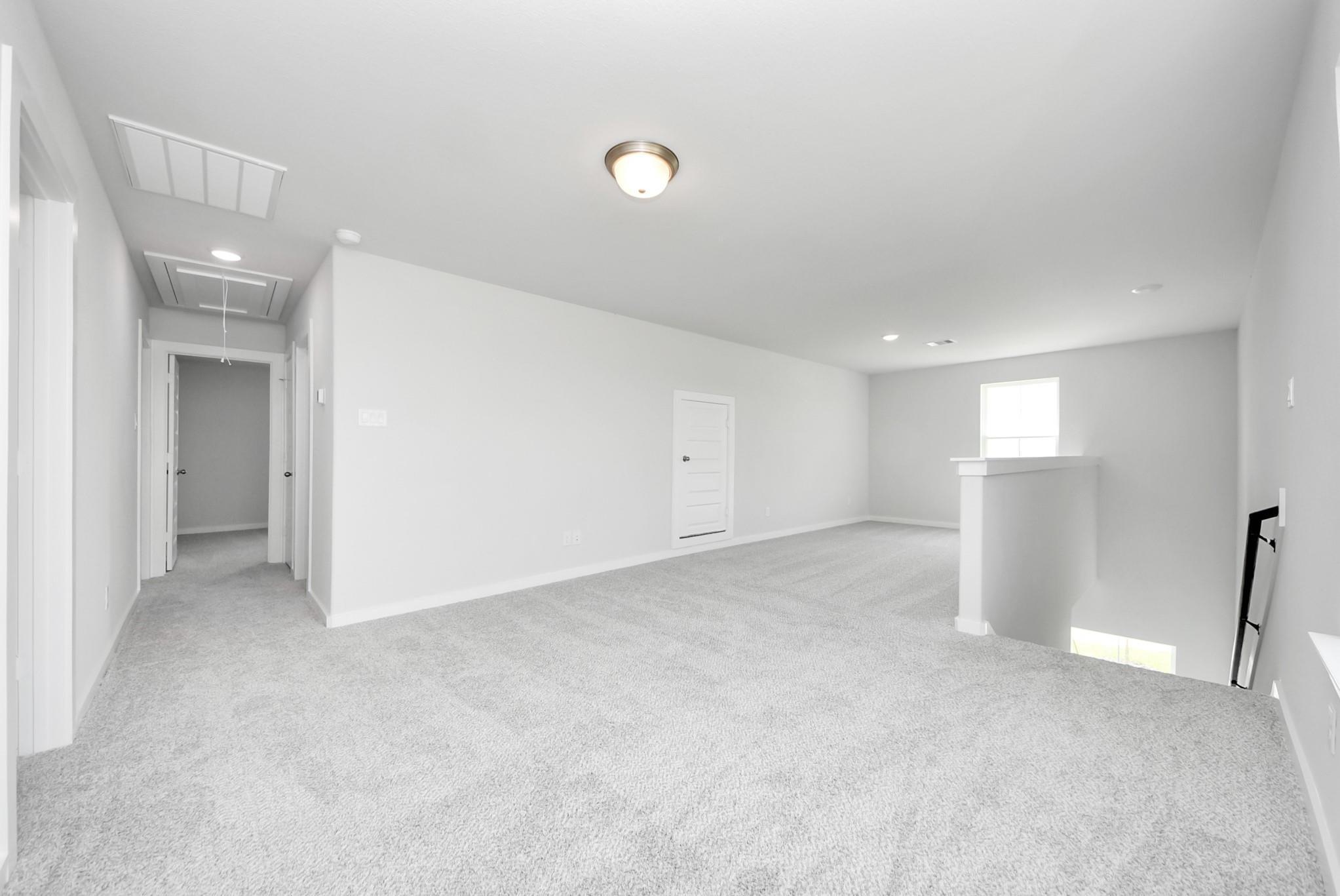 Spacious carpeted game room in The Verano B floor plan by Davidson Homes in Sunterra, Katy, Texas.