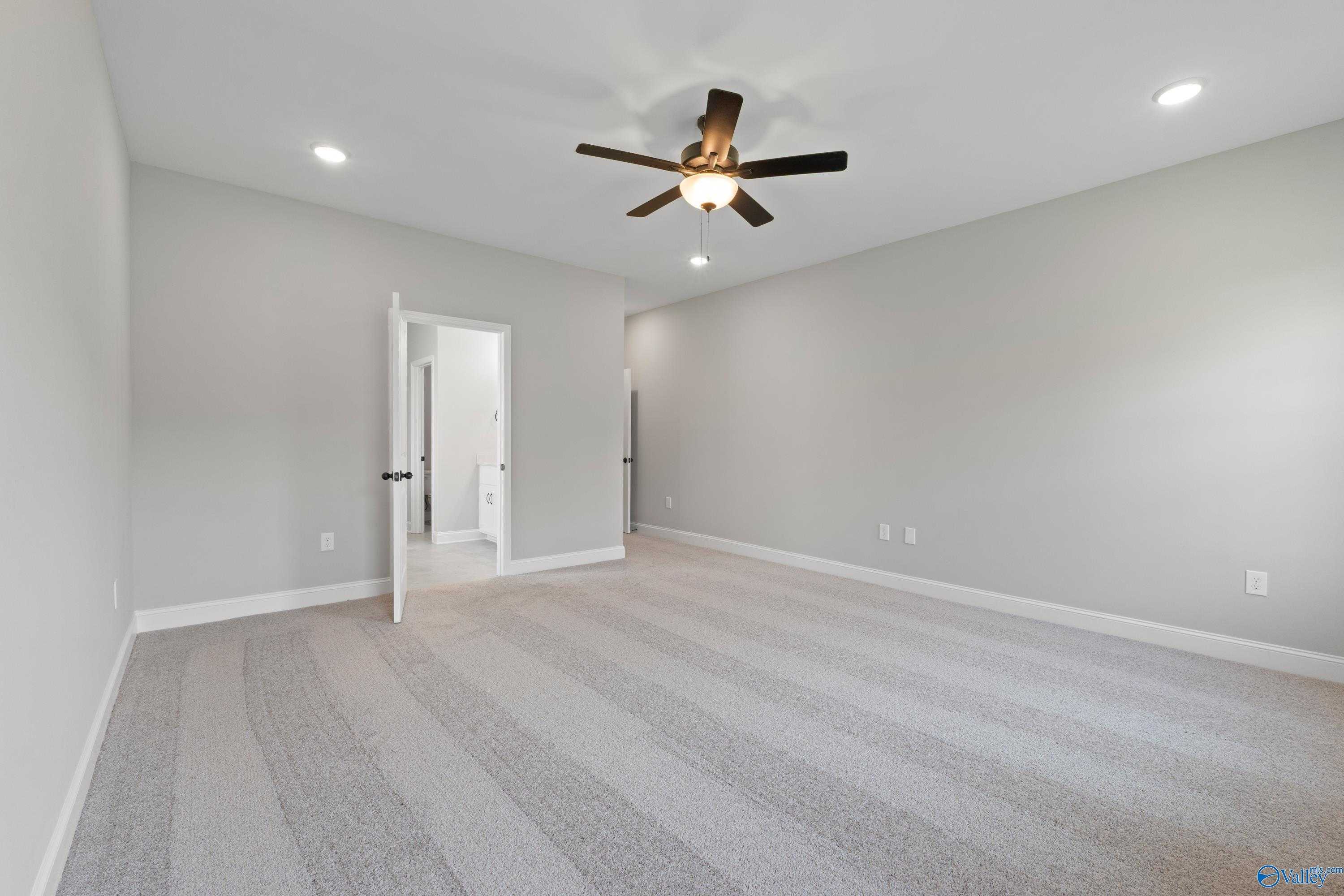 Spacious bonus room with gray walls, plush carpet, ceiling fan, and open bathroom door in Davidson Homes The Rockford, Toney, Alabama