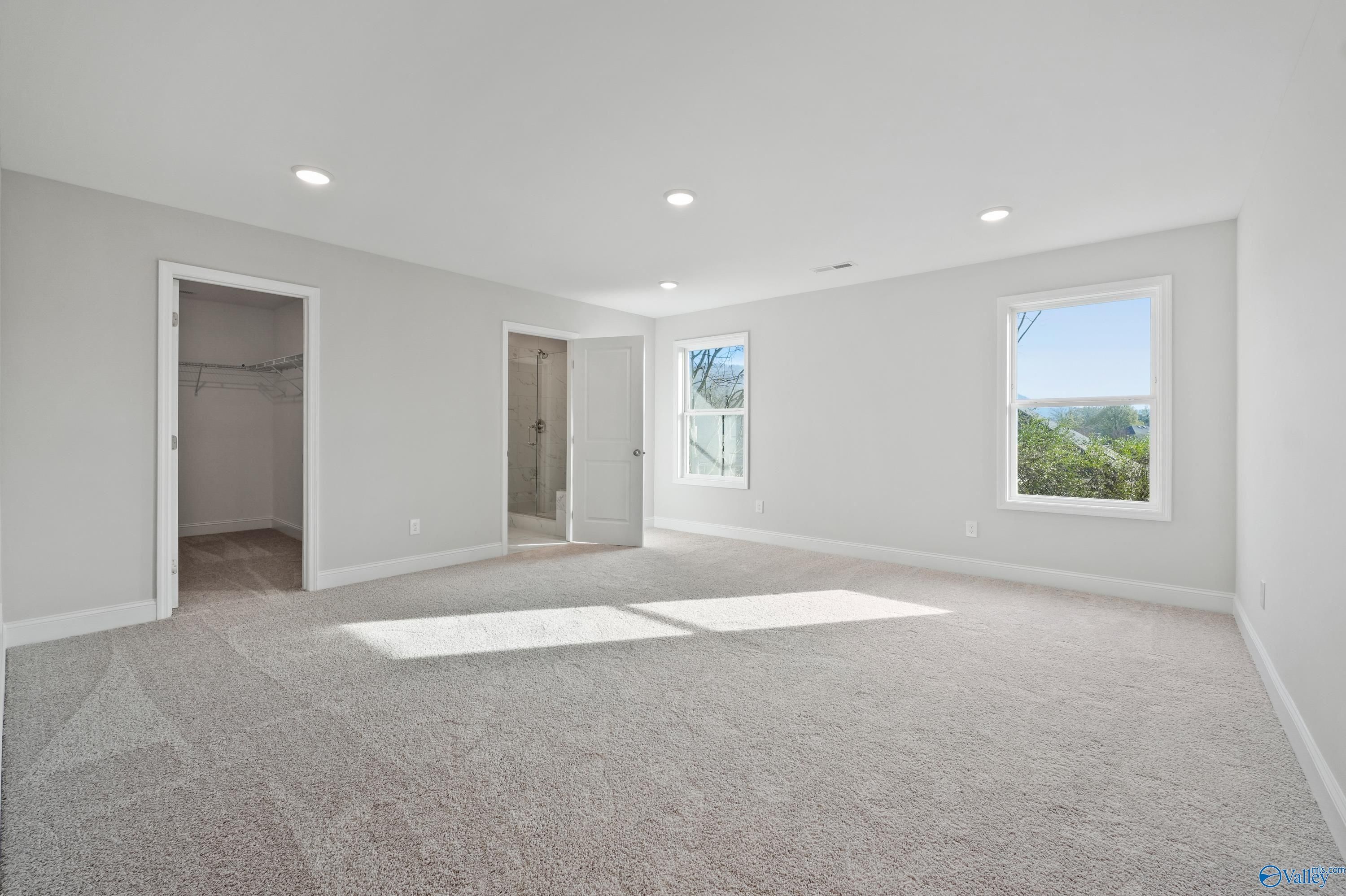 Spacious master bedroom with walk-in closet, en-suite bath, and scenic window views in Davidson Homes The Camden, Huntsville, Alabama
