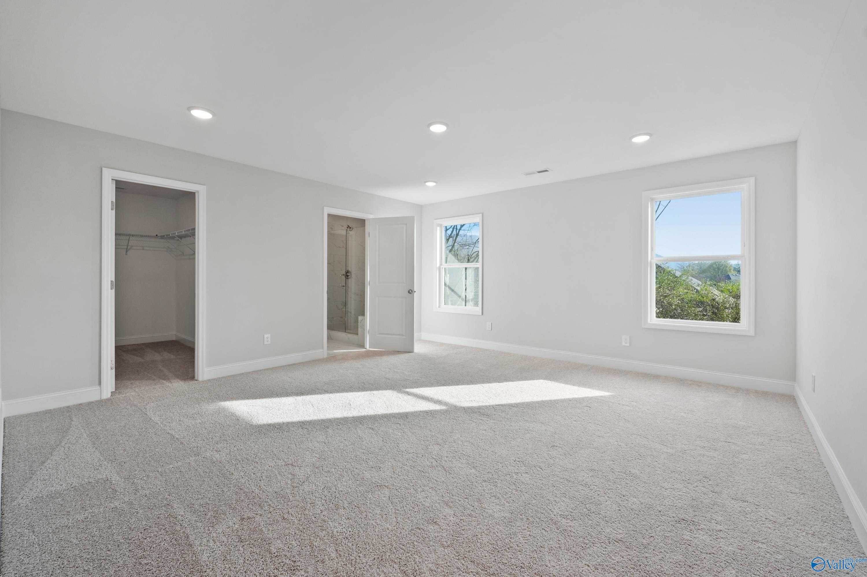 Spacious master bedroom with walk-in closet, en-suite bath, and scenic window views in Davidson Homes The Camden, Huntsville, Alabama