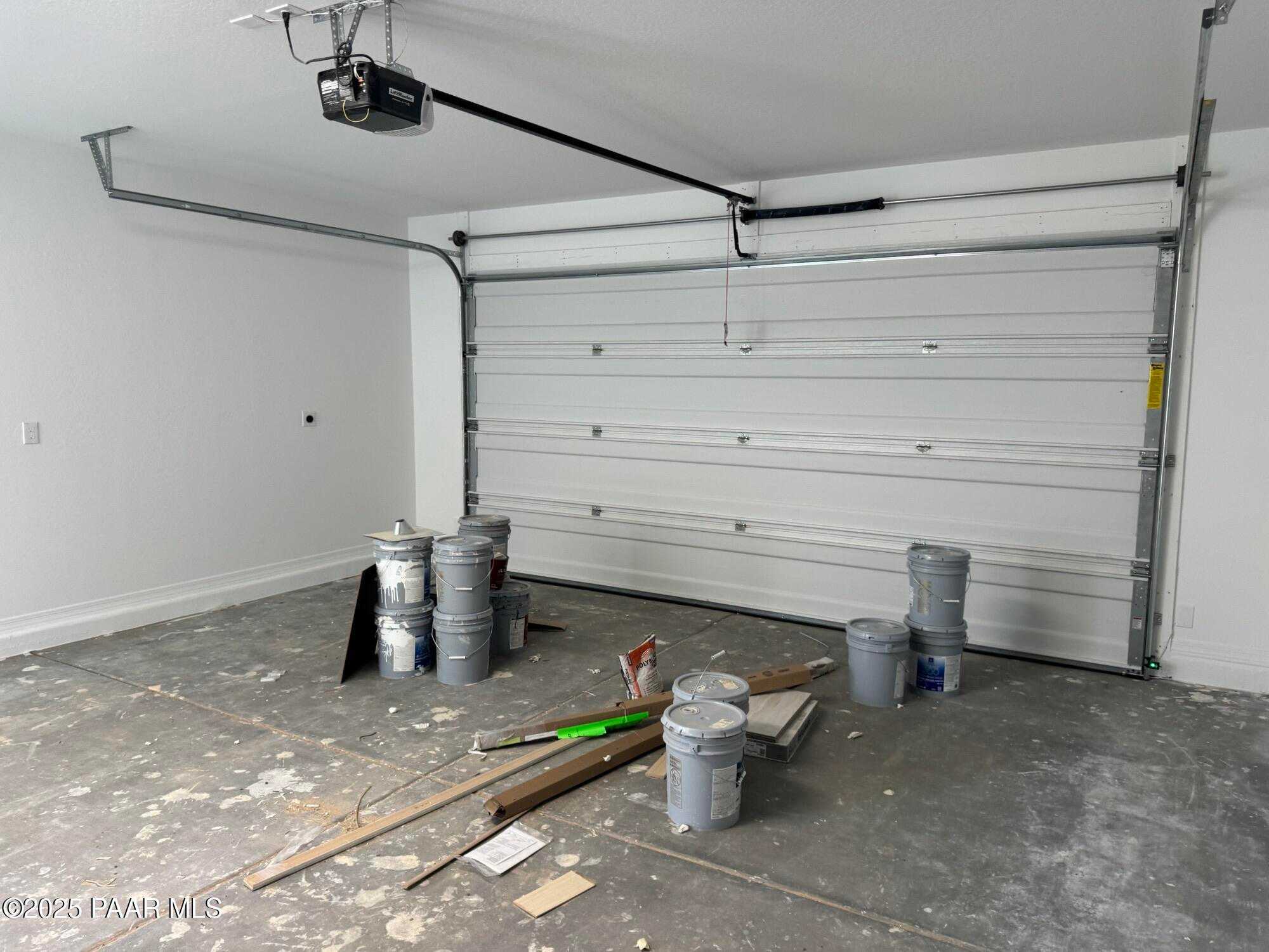 Spacious 3-car garage with painting supplies, open door, and concrete floor in Davidson Homes The Sheridan II B, Prescott, AZ