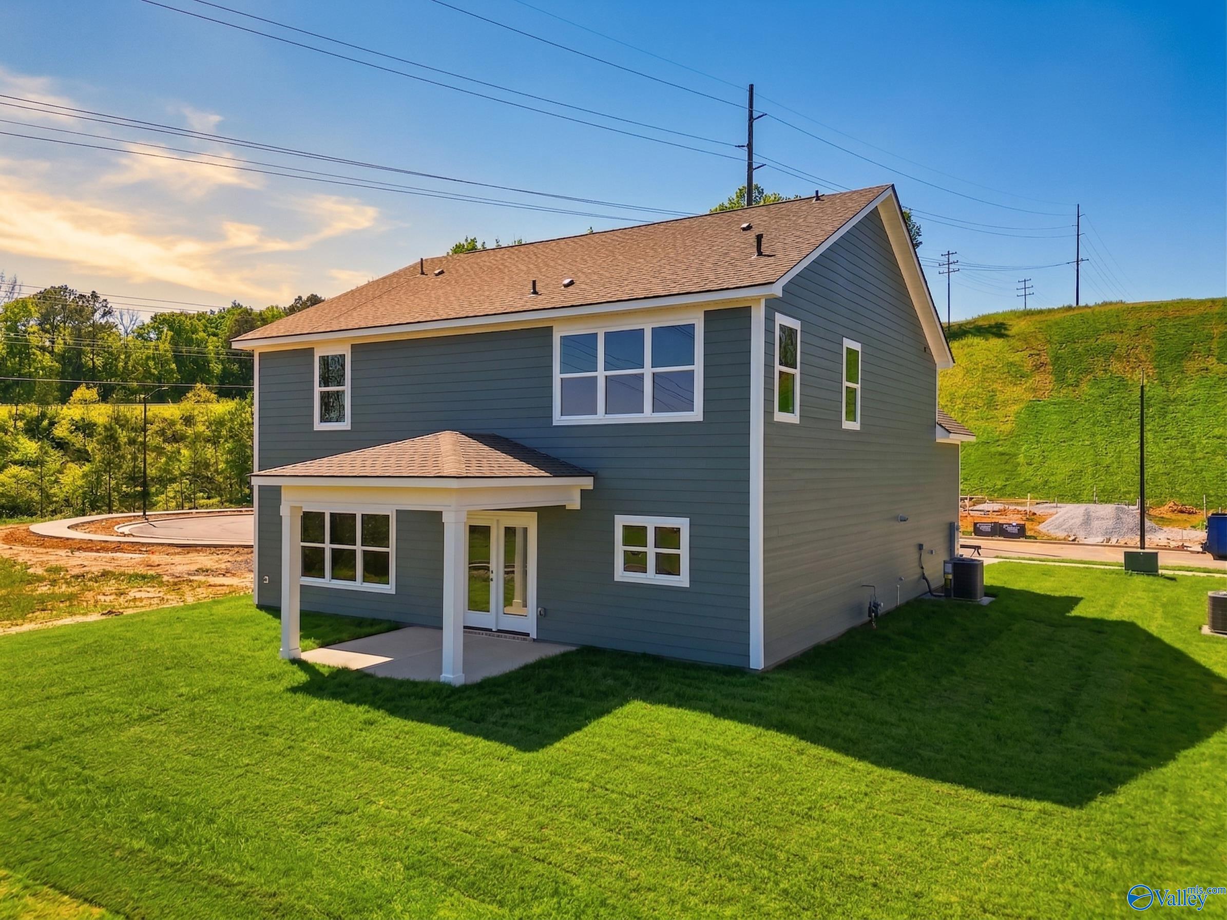 Two-story Chelsea D home exterior with blue siding, covered front porch, and green lawn in Noble Ridge, Cullman, Alabama