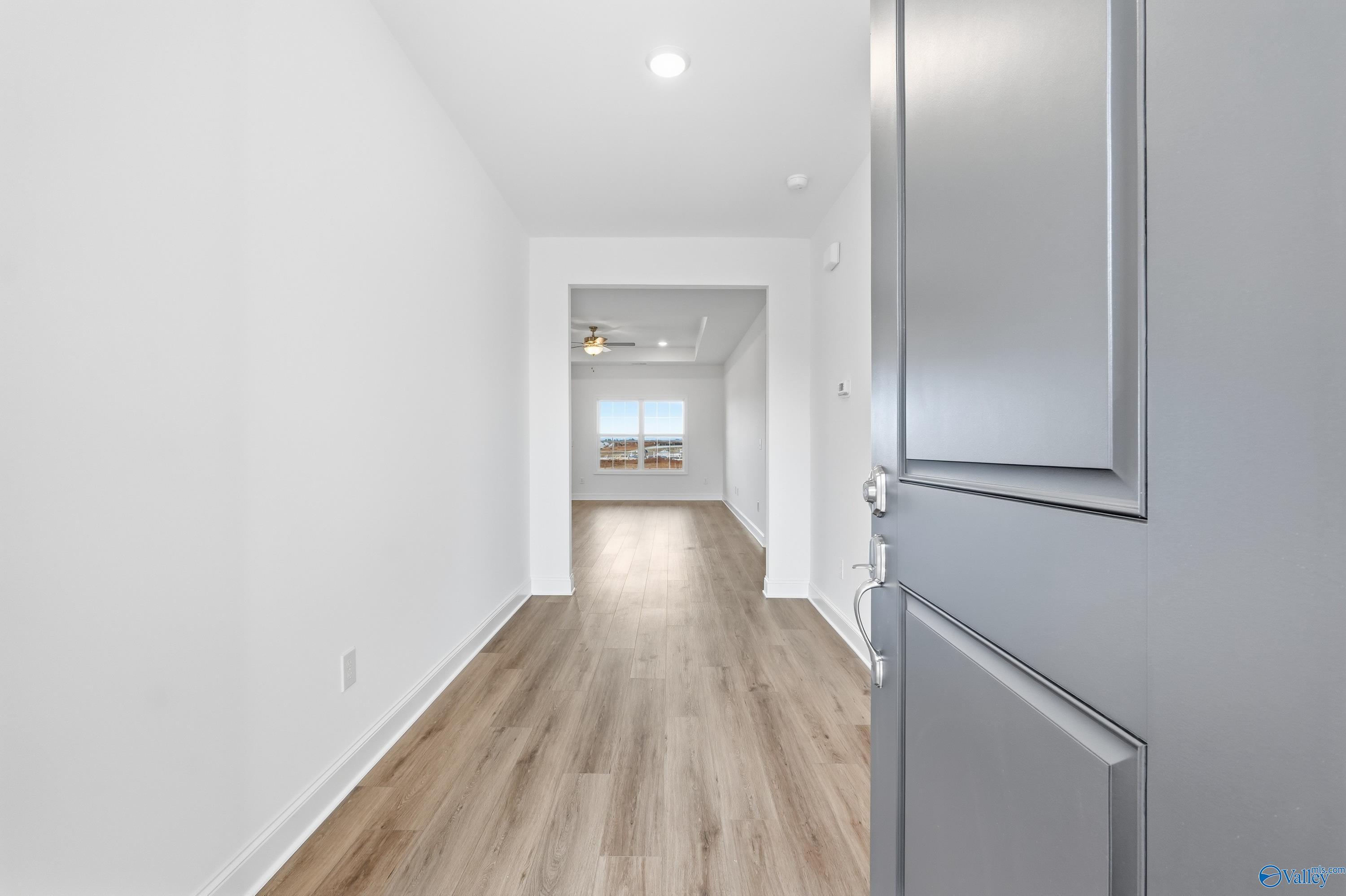 Bright hallway with light wood floors, white walls, recessed lighting, and window views in Davidson Homes The Montgomery C, Harvest, Alabama