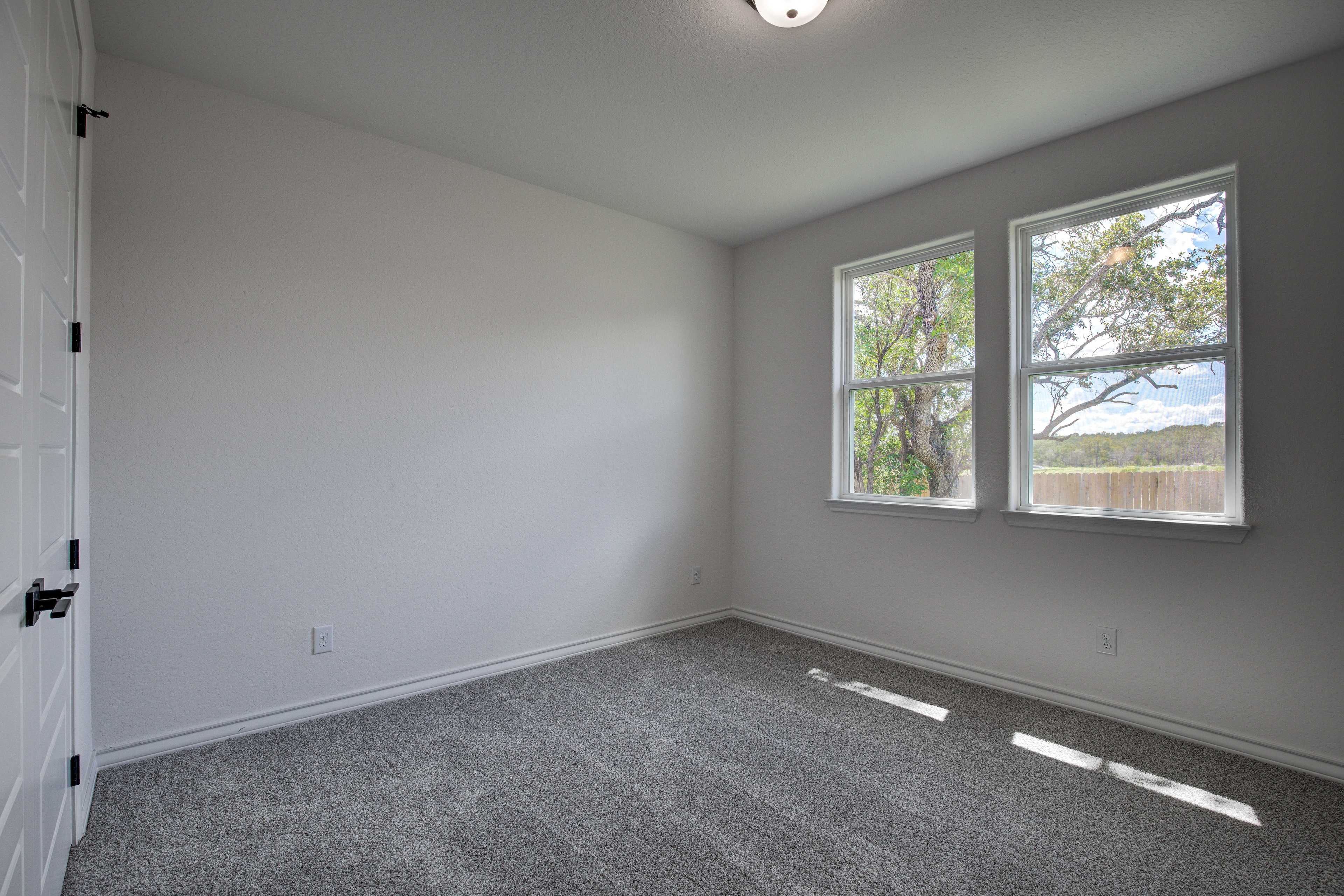 Spacious secondary bedroom in The Lanier with gray carpet, white walls, large double windows, and natural light