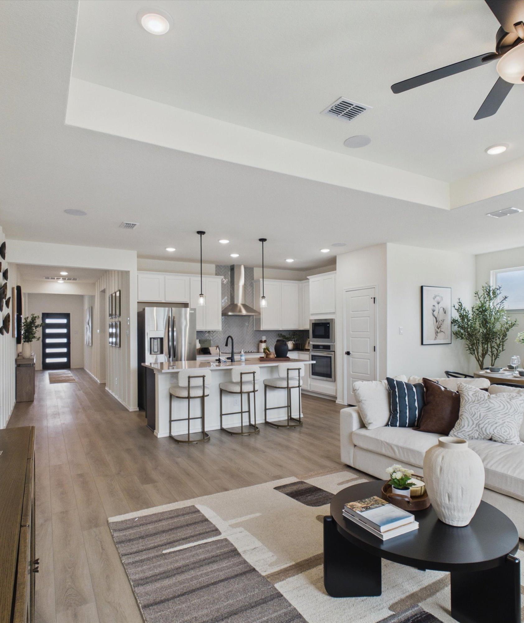 Open-concept kitchen and living room in Rayburn Valley San Antonio TX home with white island, hardwood floors, orange sofa, ceiling fan