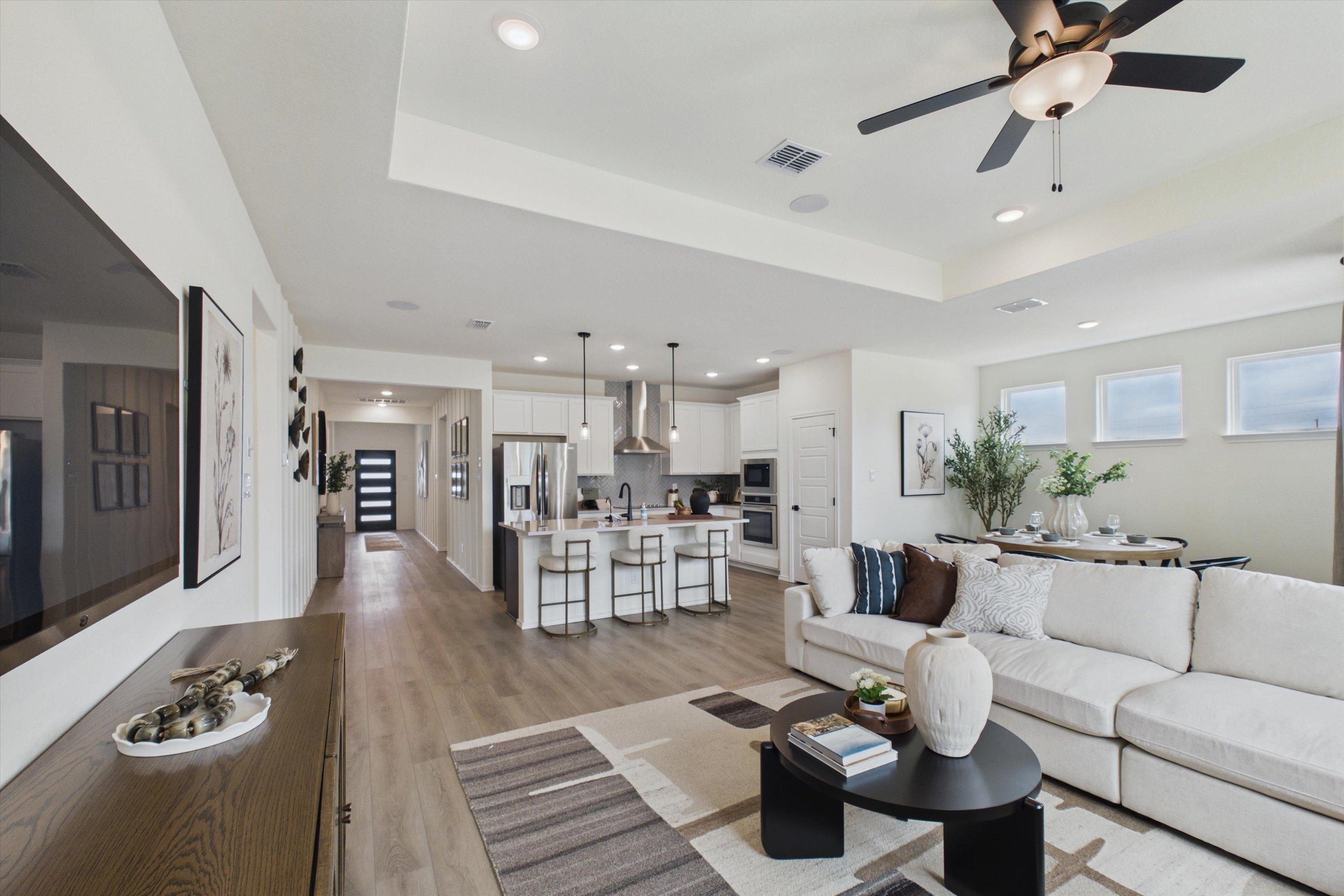 Open-concept kitchen and living room in Rayburn Valley San Antonio TX home with white island, hardwood floors, orange sofa, ceiling fan