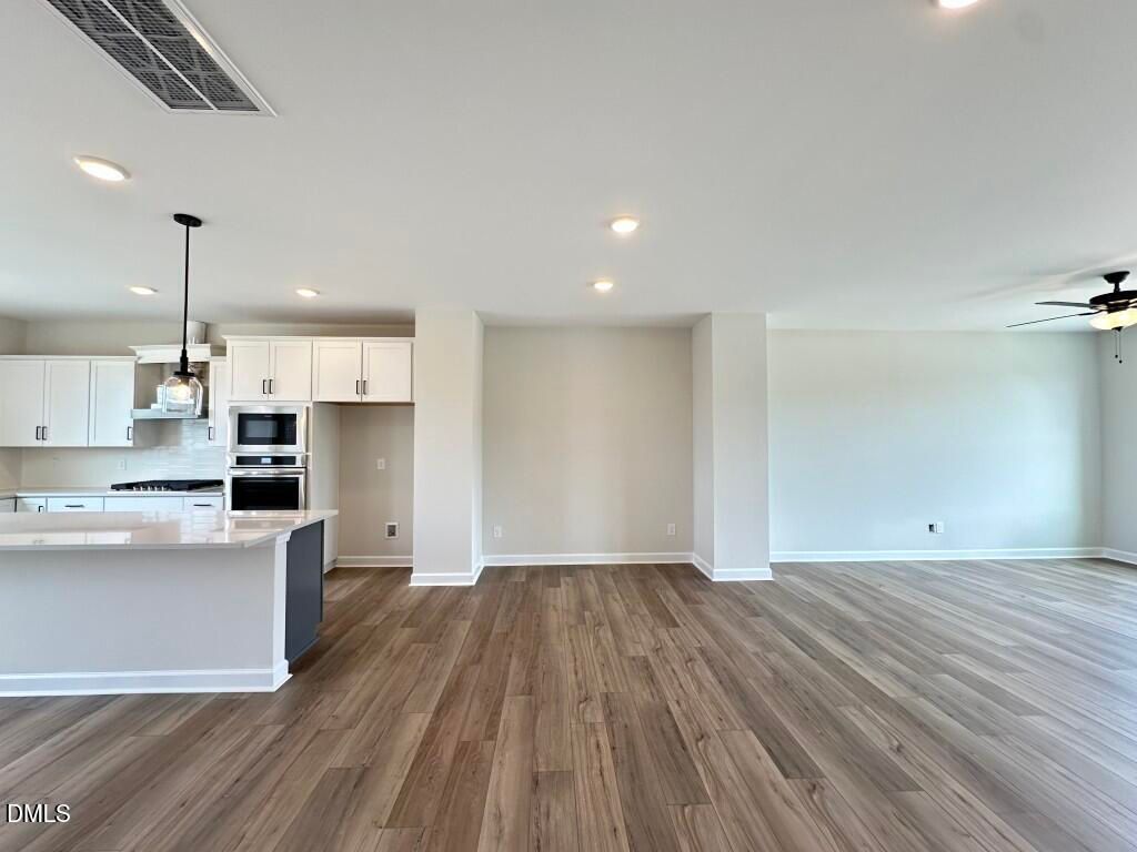 Modern open-concept kitchen with white cabinets, quartz island, stainless appliances in The Avery floor plan by Davidson Homes, Knightdale, NC