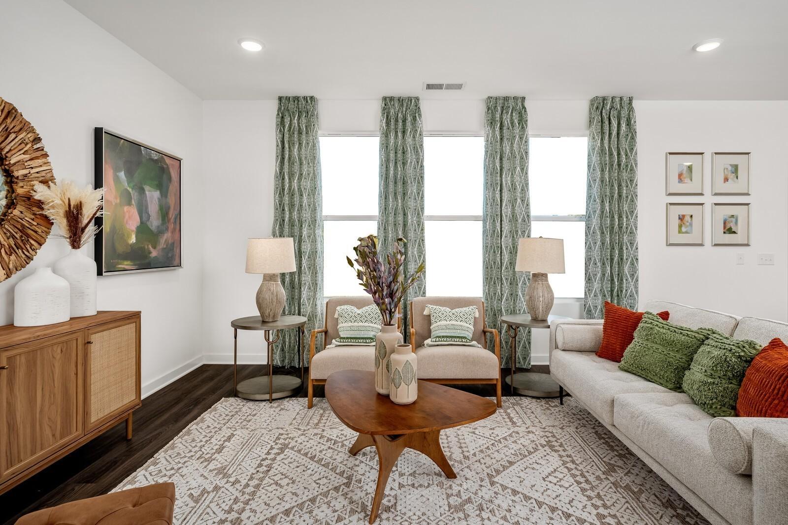 Cozy living room with beige sofa, armchairs, wooden coffee table, and green curtains in Davidson Homes The Gordon C, White House, TN