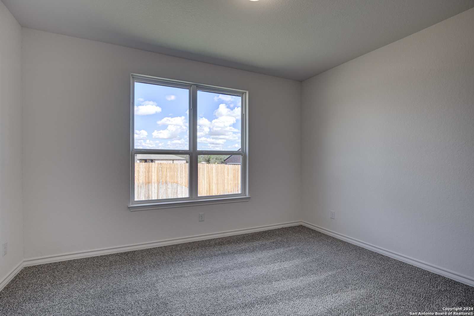 Bright bedroom with large window, beige carpet, and natural light in Davidson Homes The Garner B, Castroville, Texas